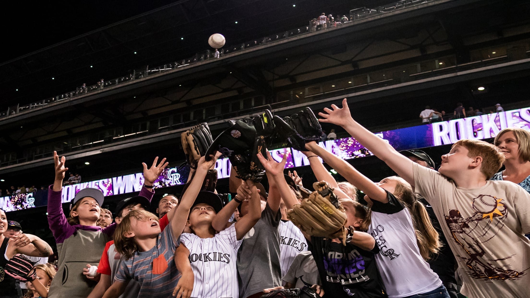 Young fans catching a baseball on field level