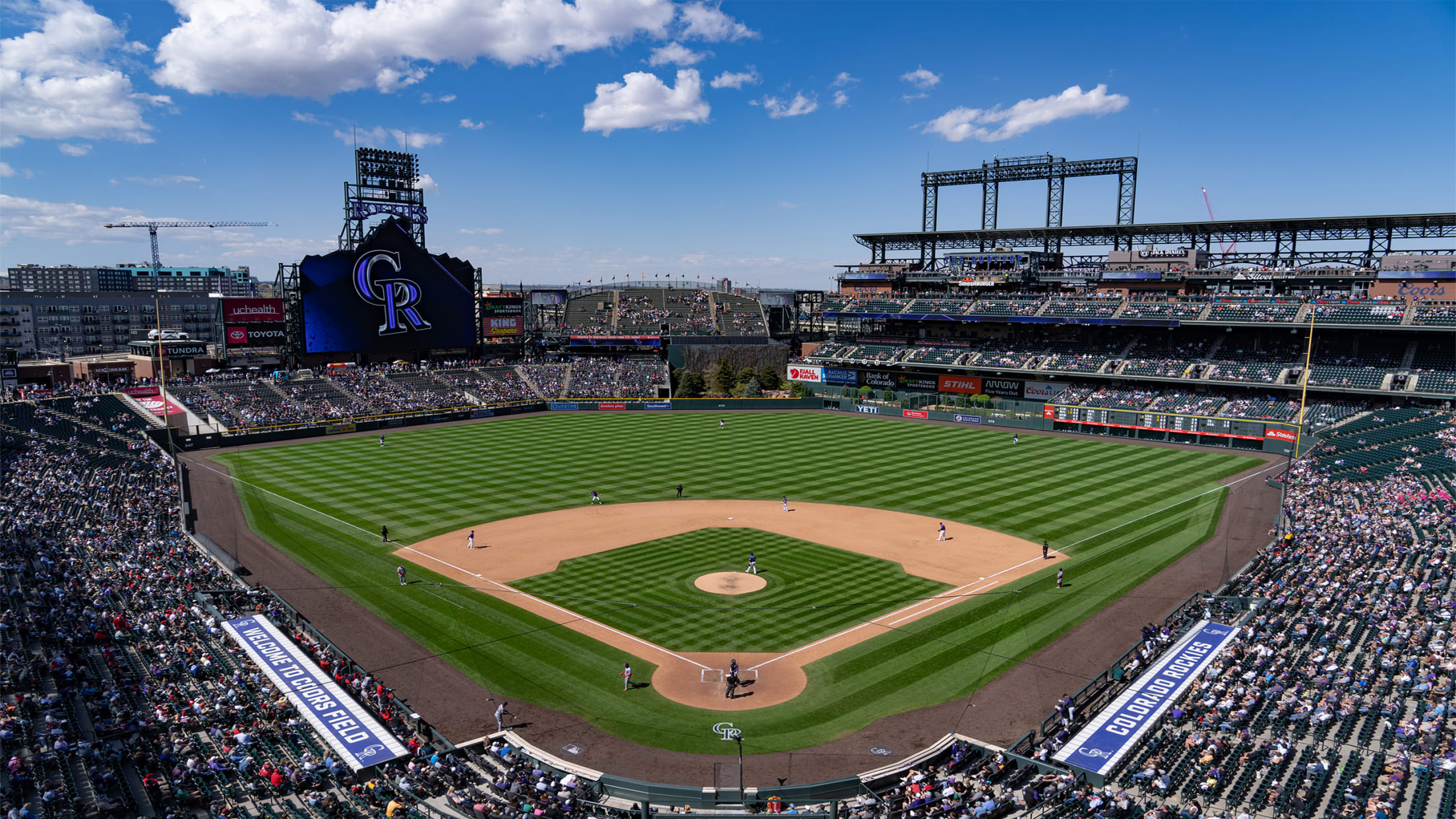View from the upper level seats watching the players on field with blue skies