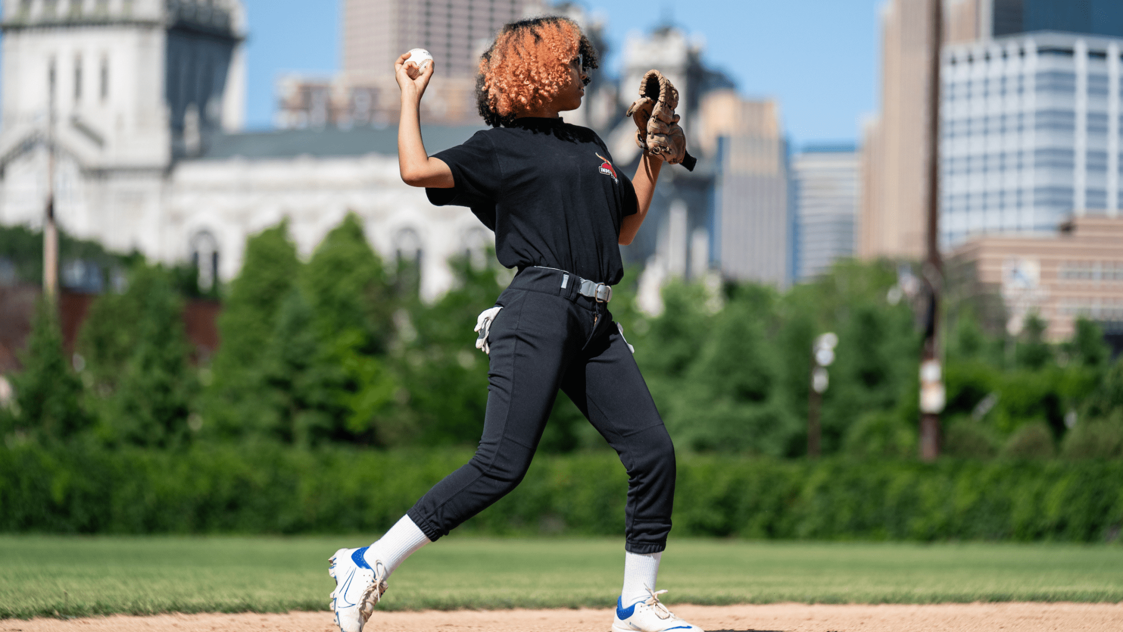 Girl wearing a baseball glove on left hand and about to throw a ball with right hand.