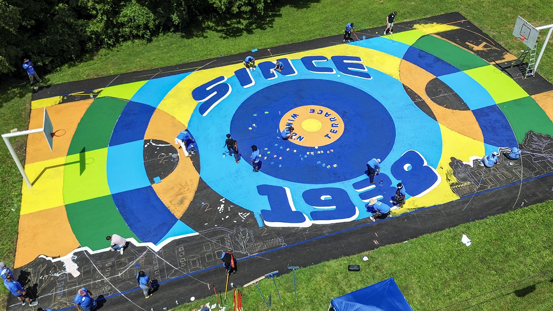 A newly repaired basketball court featuring a brightly colored mural.