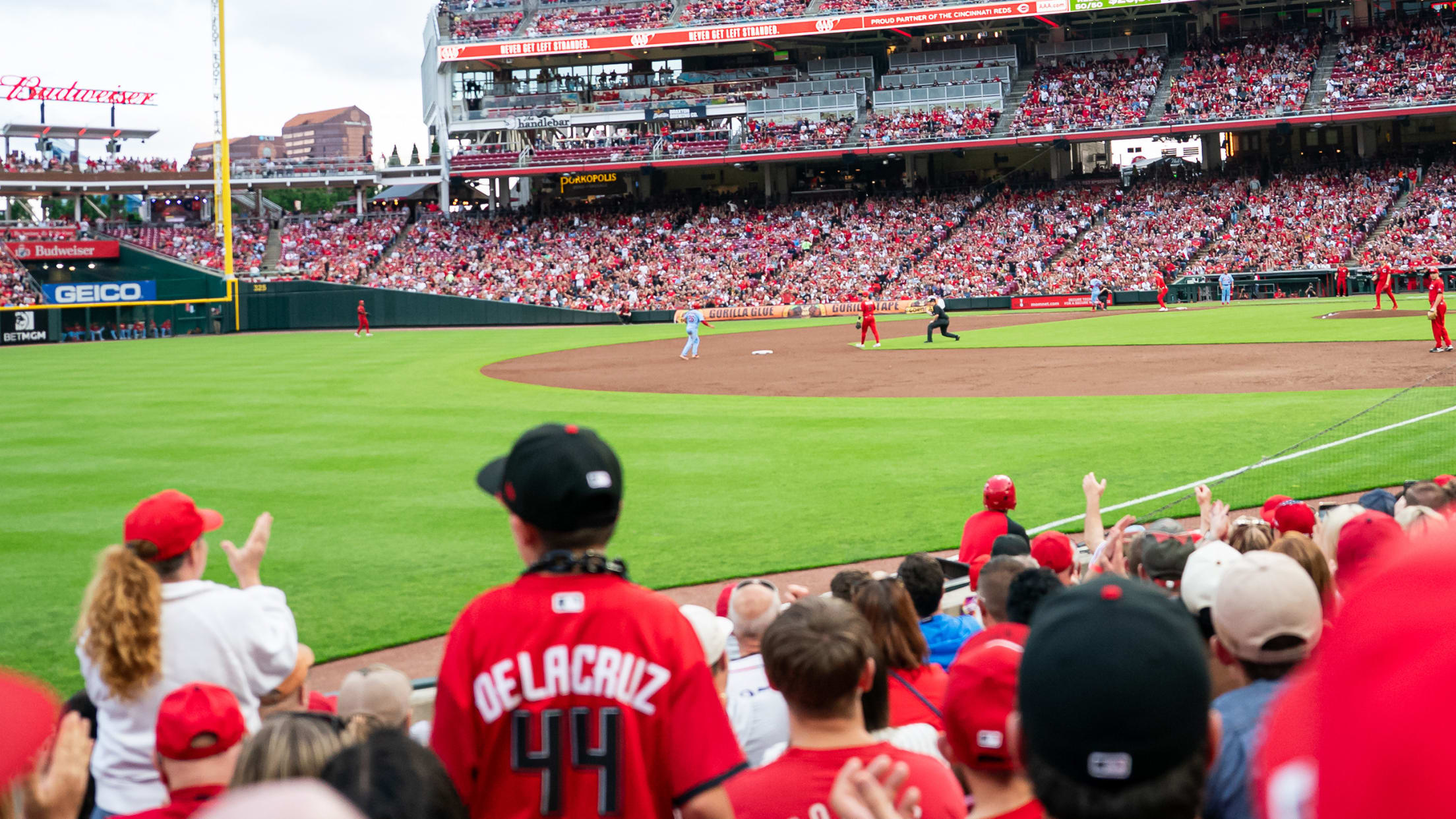 Fans in lower level seats near shallow left field watching the Reds game.
