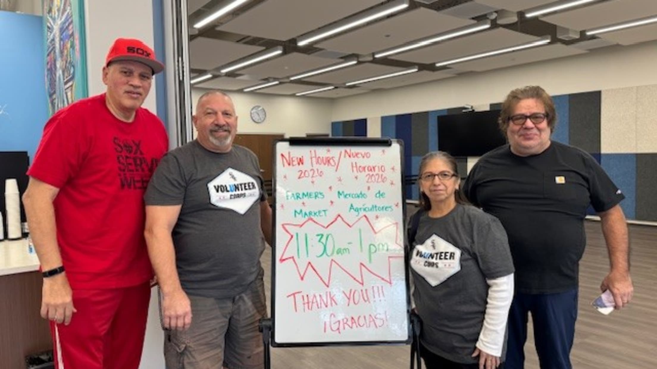 White Sox volunteers pose with a sign for their new hours.