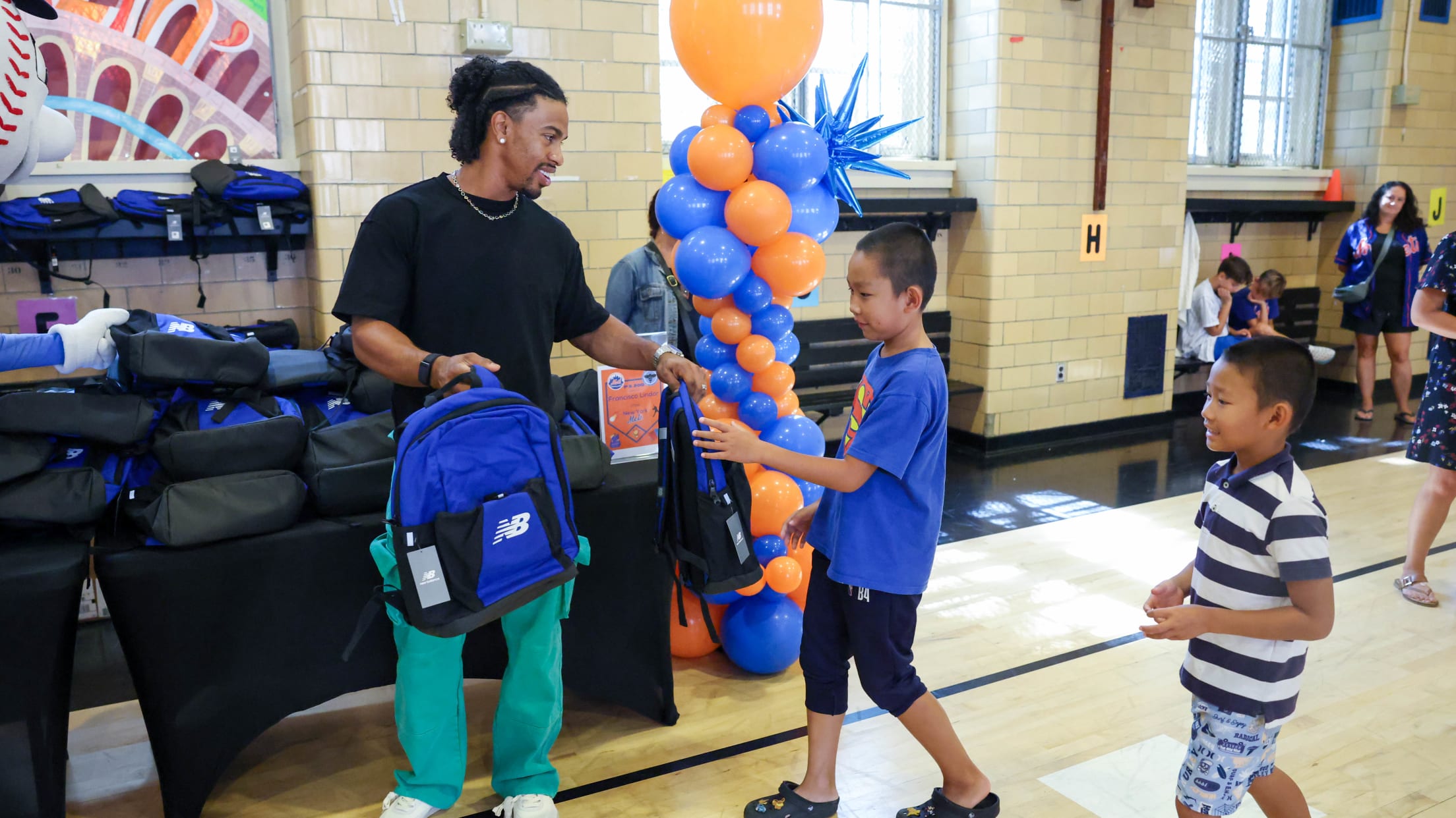 Francisco Lindor hands students backpacks at a giveaway event at a New York City school.