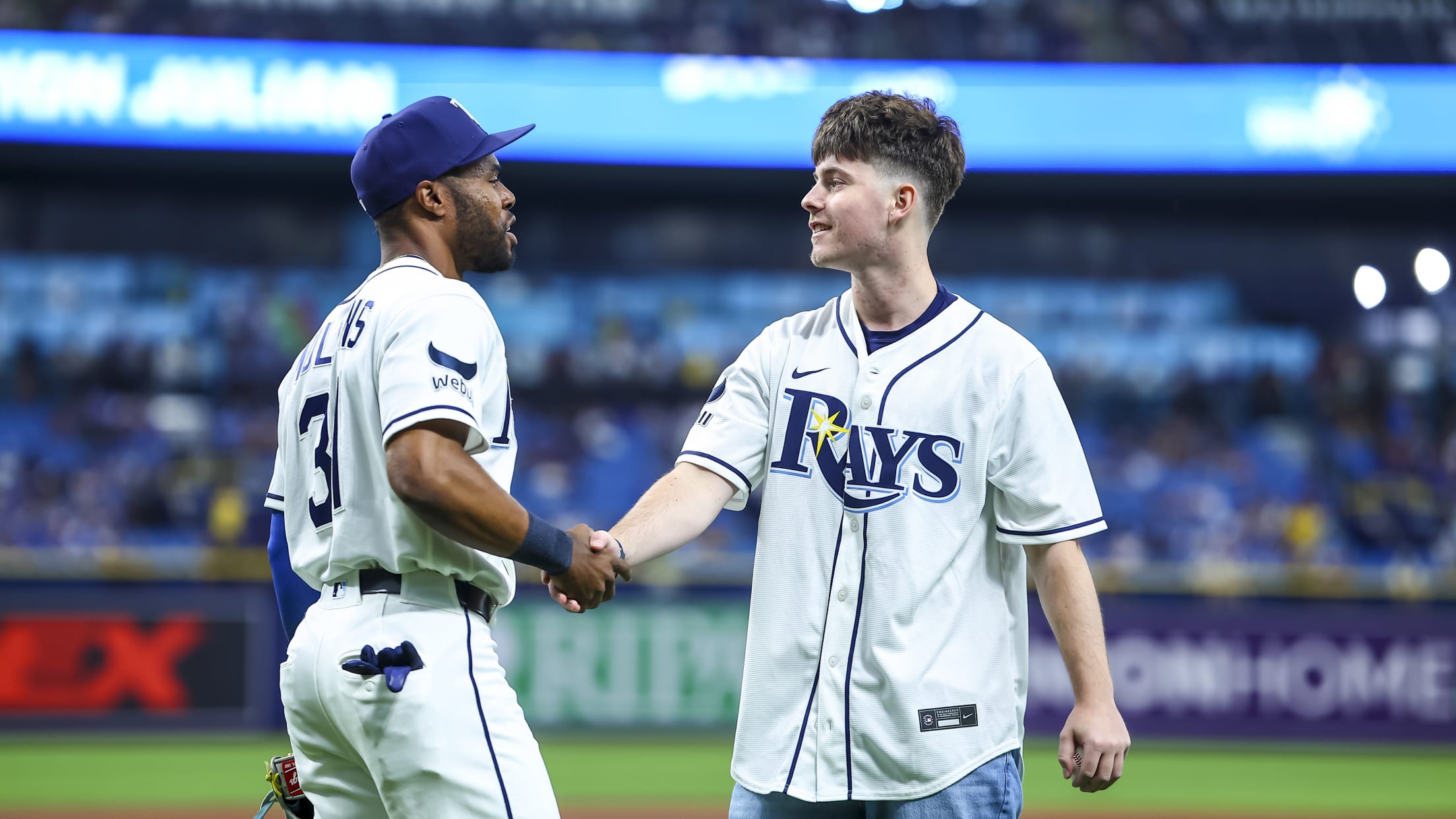 Cedric Mullins shakes hands with a fan on the field at Tropicana Field.
