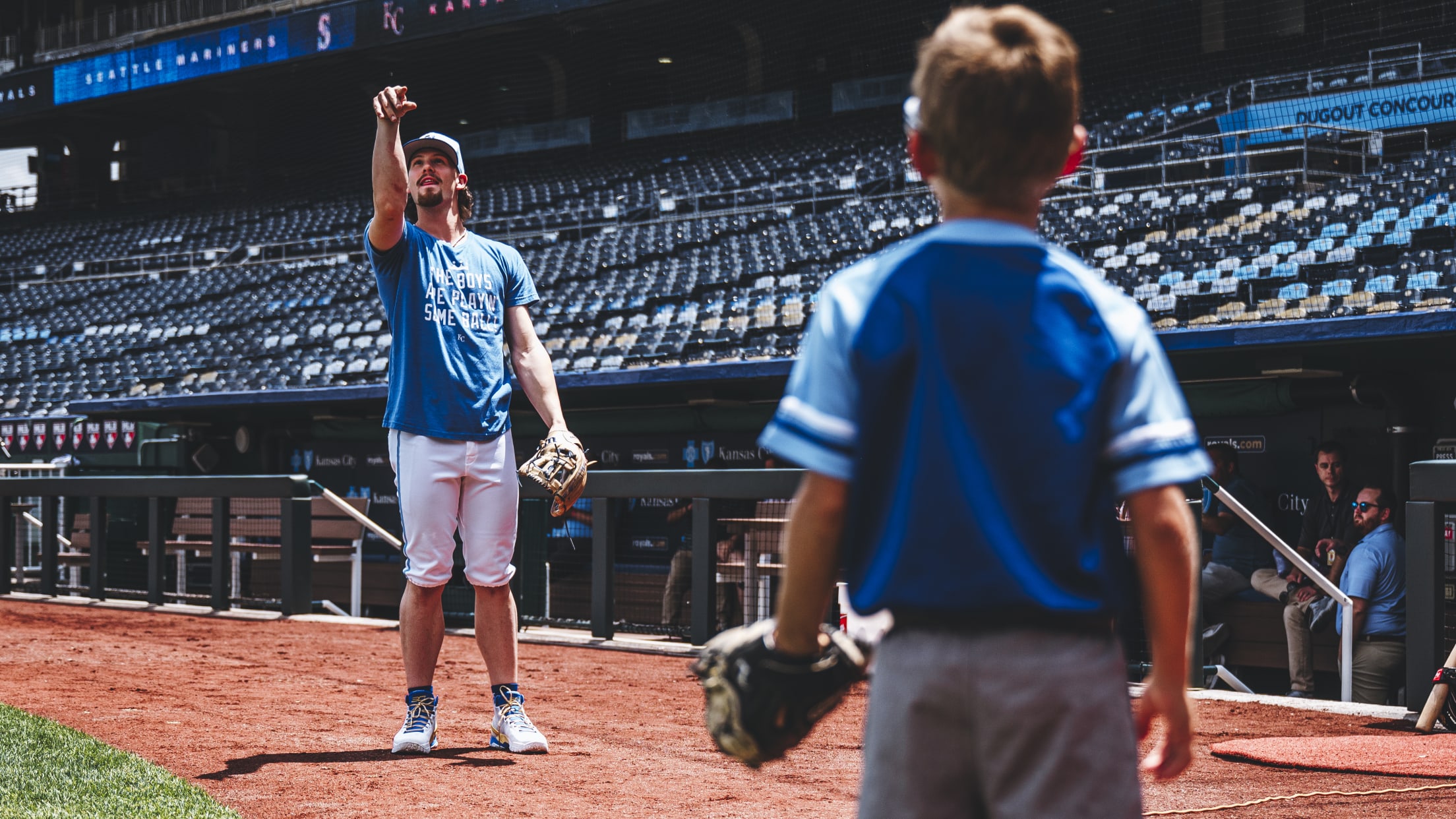 Bobby Witt Jr. plays catch with a young fan on the field.