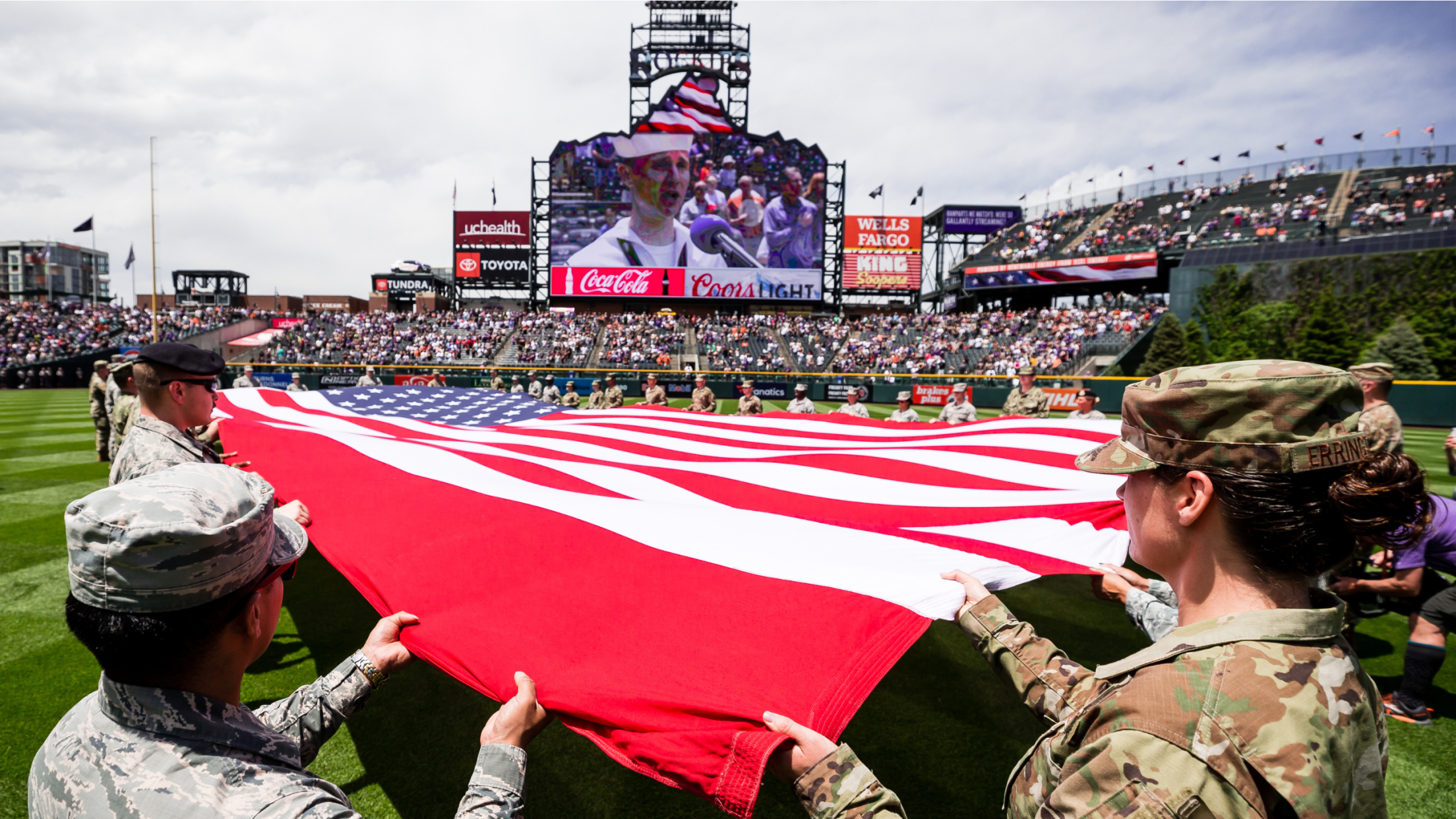 Military members holding American flag on field