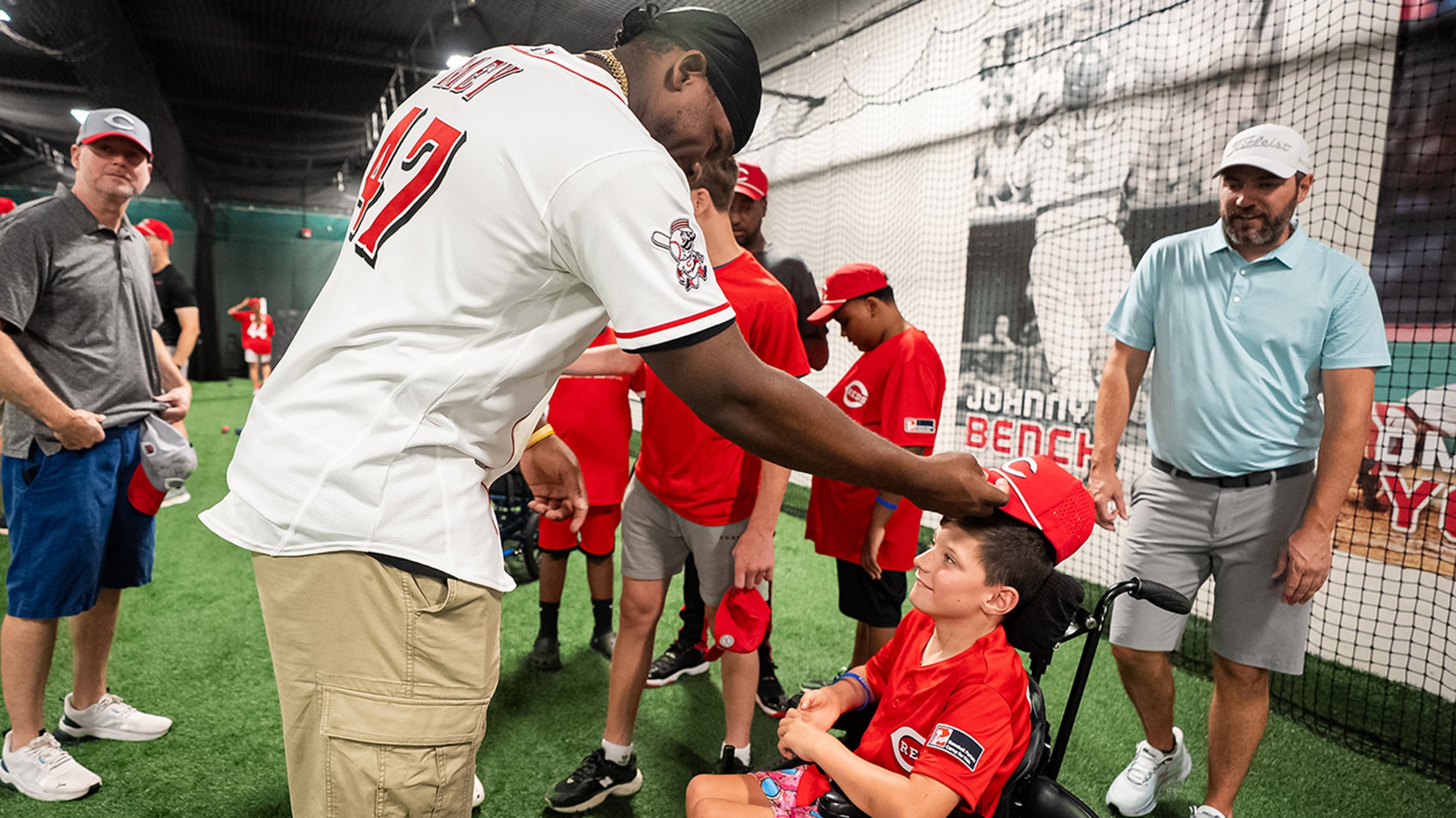 Luis Mey putting a baseball cap on one of the participants after the camp ends.