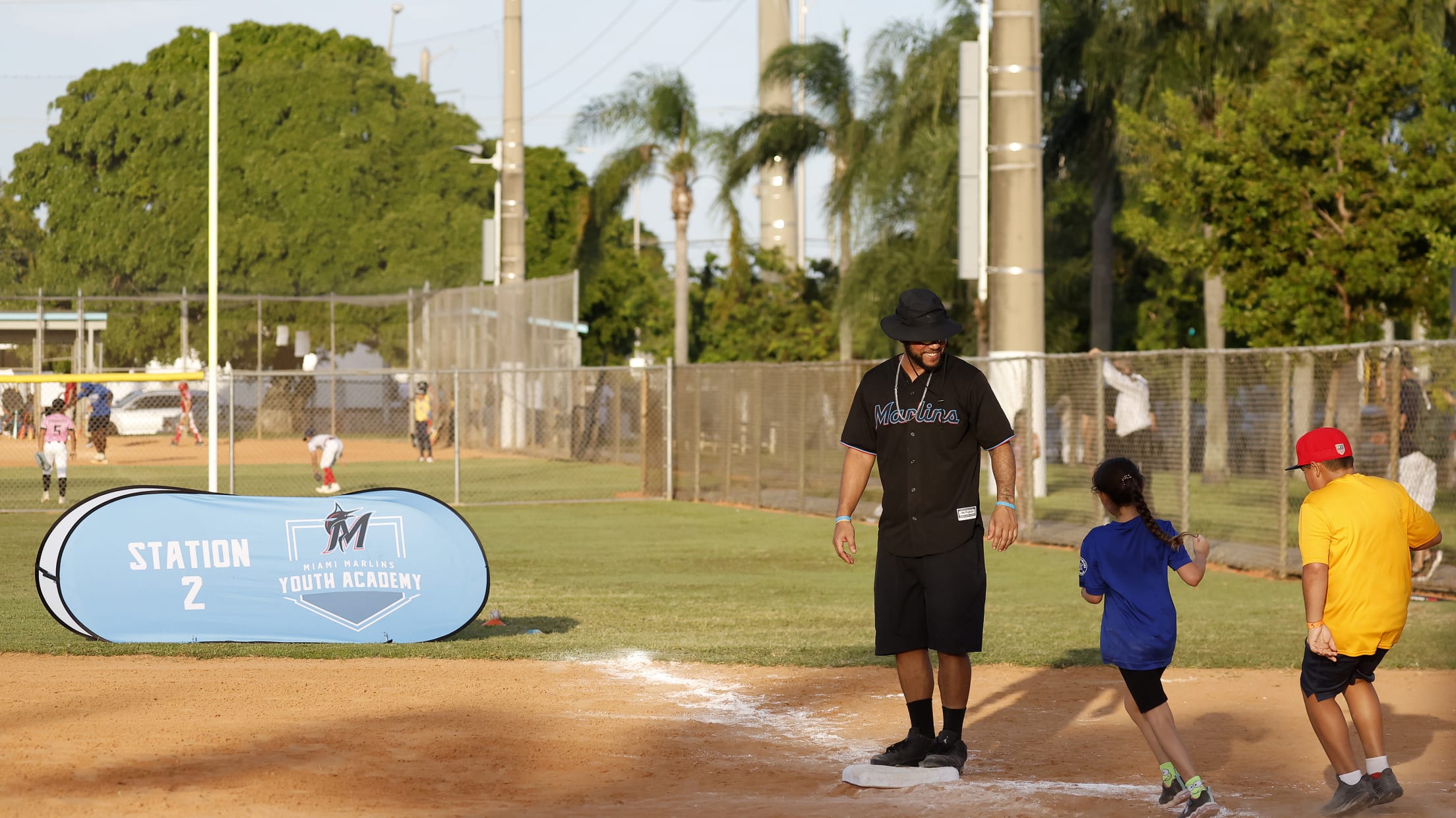 A coach watches as players run to first base.