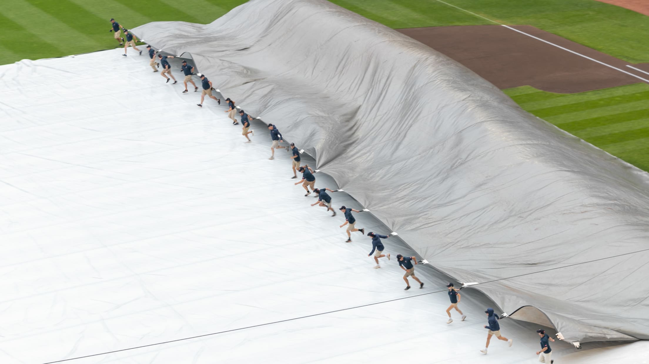 A member of grounds crew raking the field