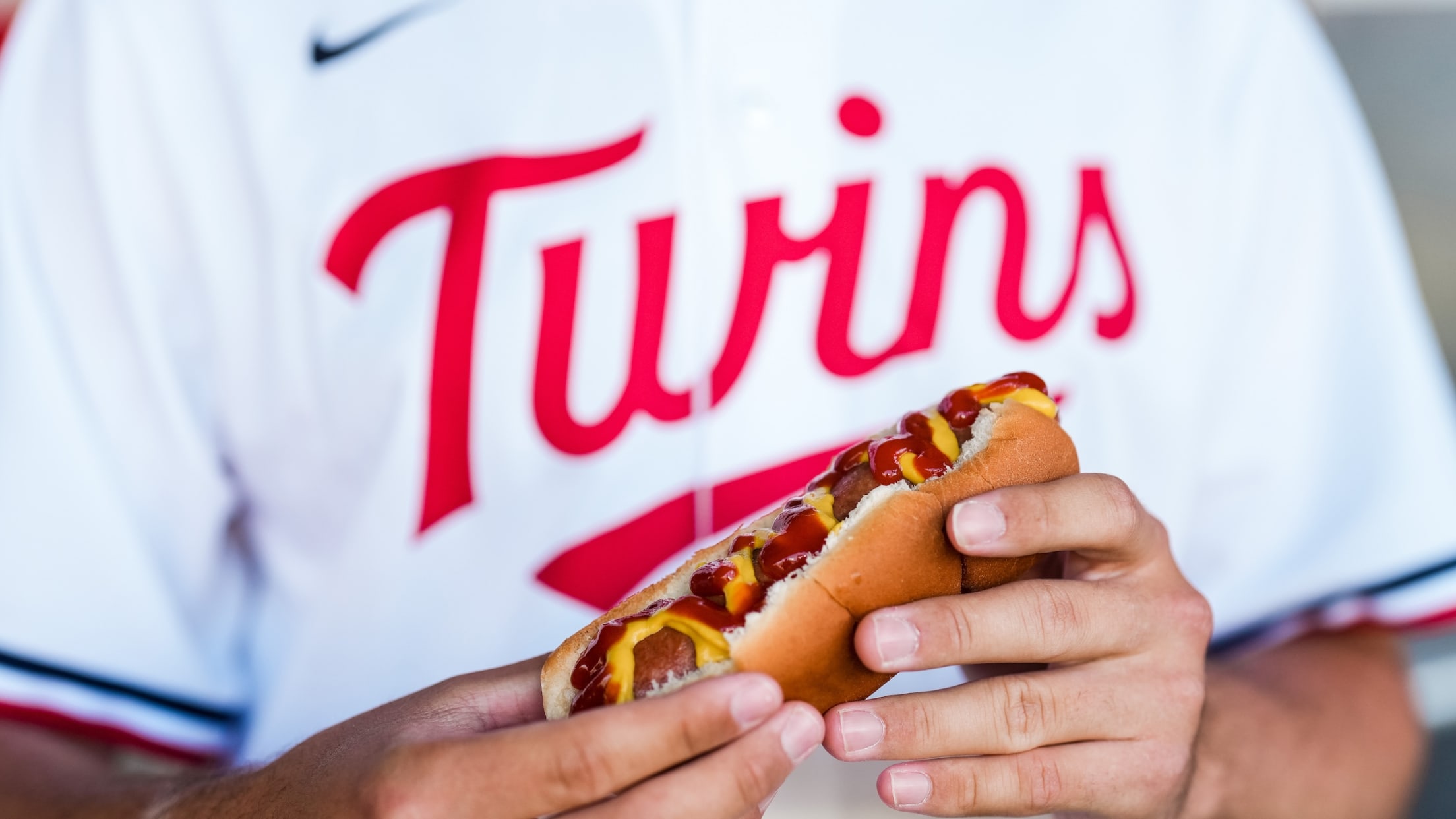 Image of a person in Twins jersey holding a hot dog