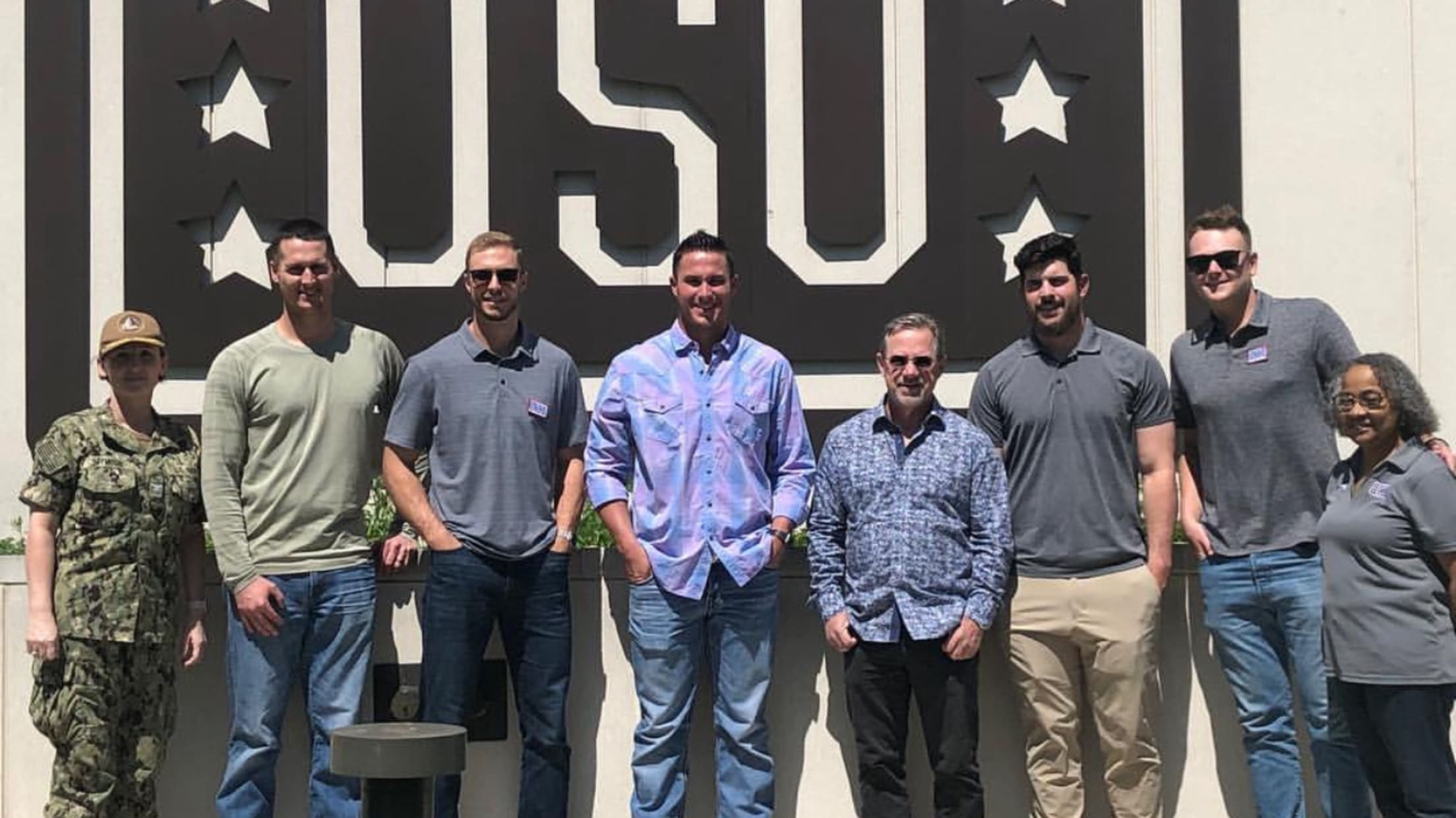 People pose for a photo in front of a USO sign.