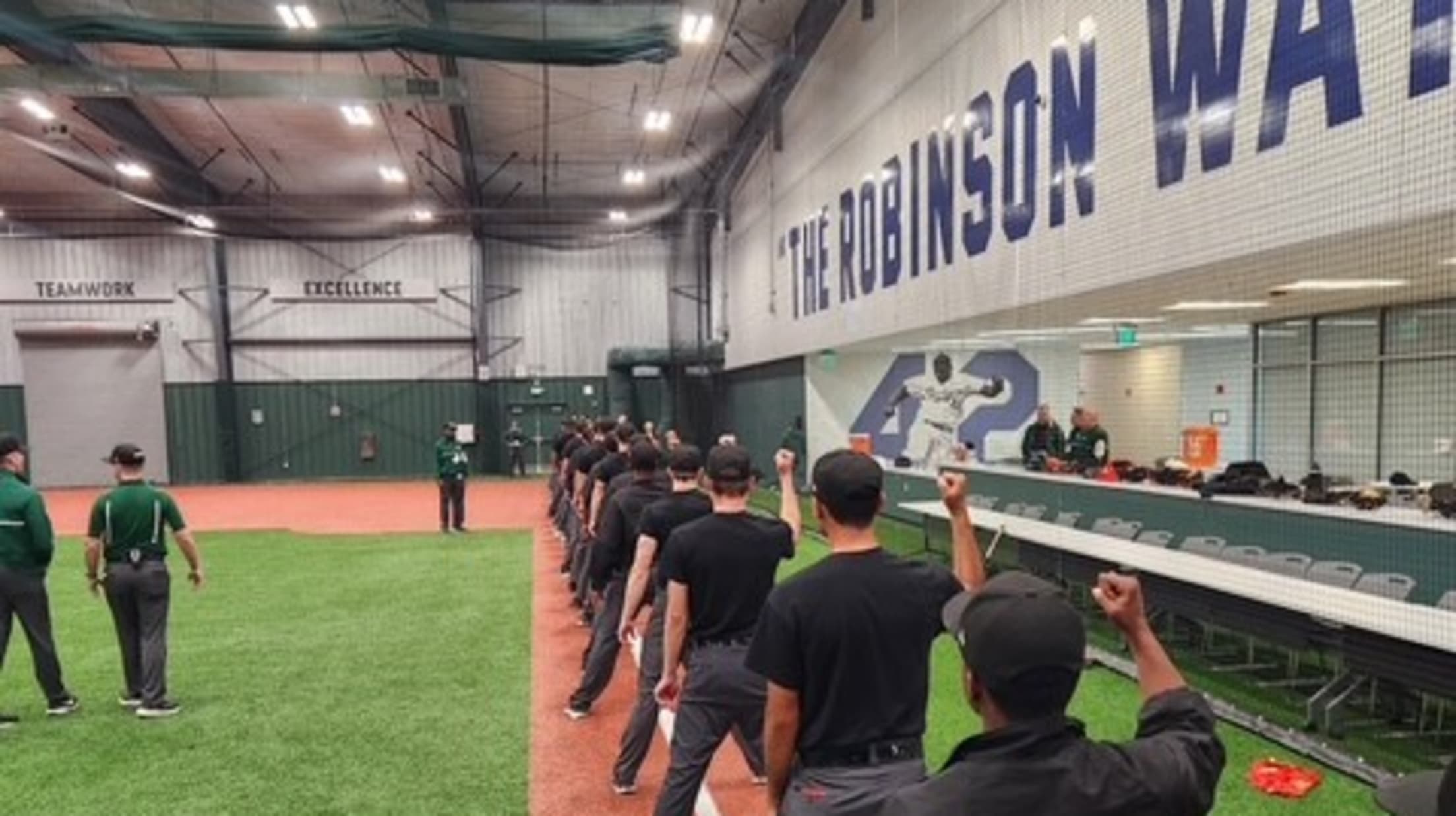 Umpires hold a strike pose in a line on an indoor baseball field.