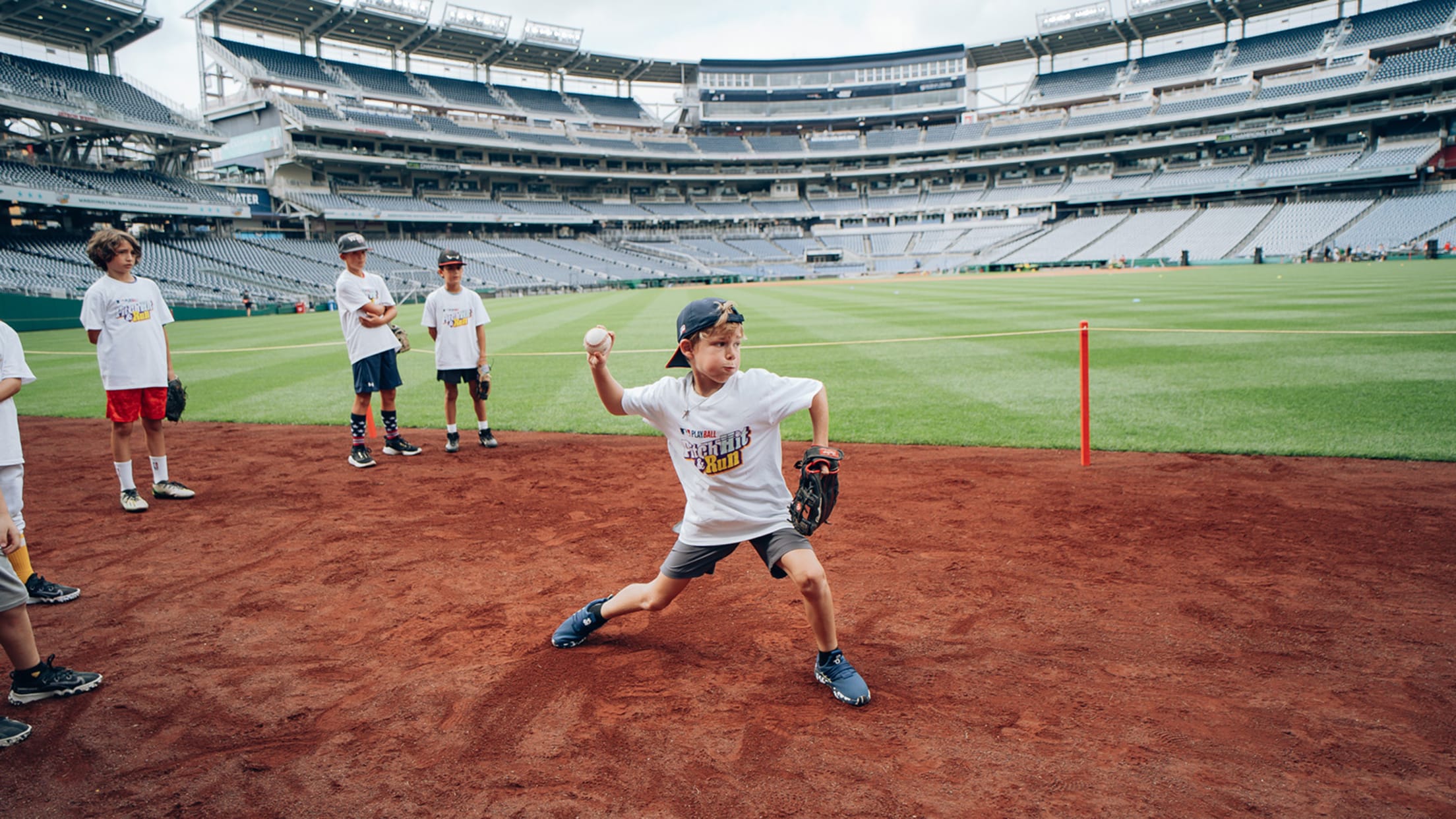 Child in backwards cap throwing on warning track