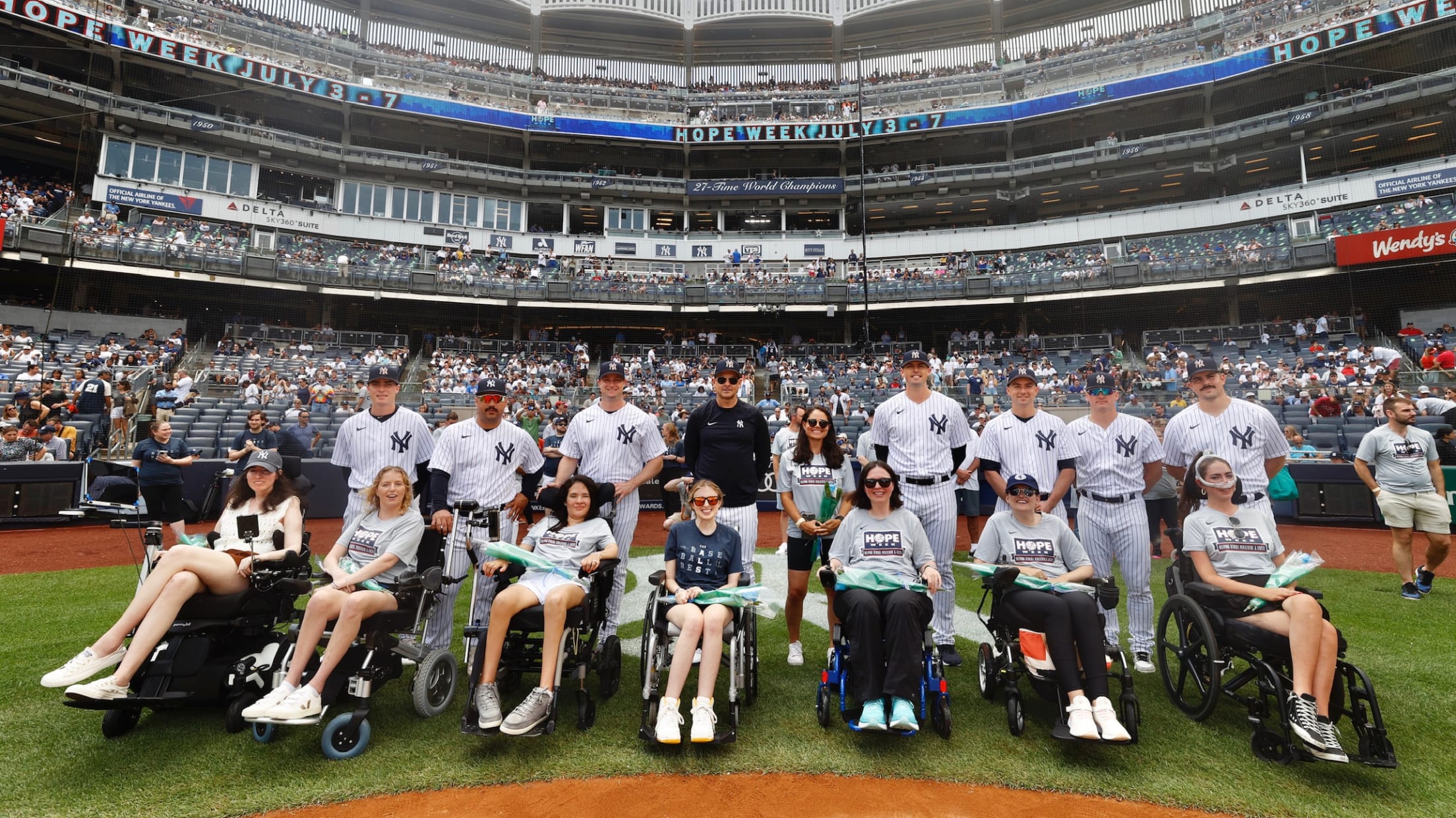 Members of the New York Yankees pose for a photo with fans in wheelchairs behind home plate at Yankee Stadium.