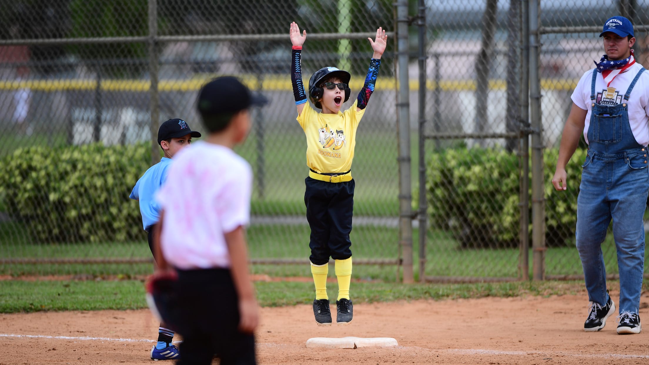 A player jumps and lifts his arms up celebrating at first base.