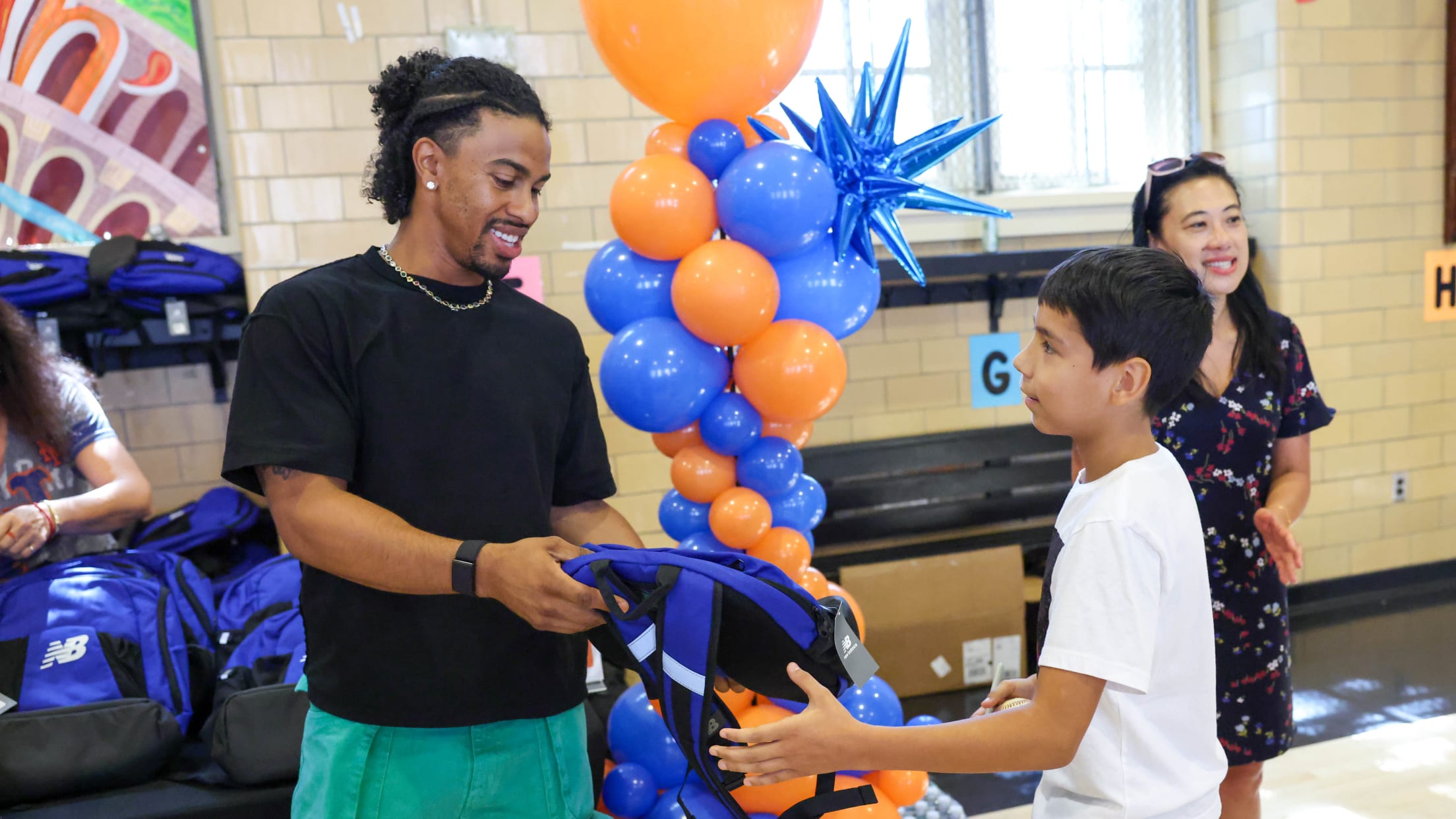 Francisco Lindor hands a student a backpack at a backpack giveaway at a New York City school.