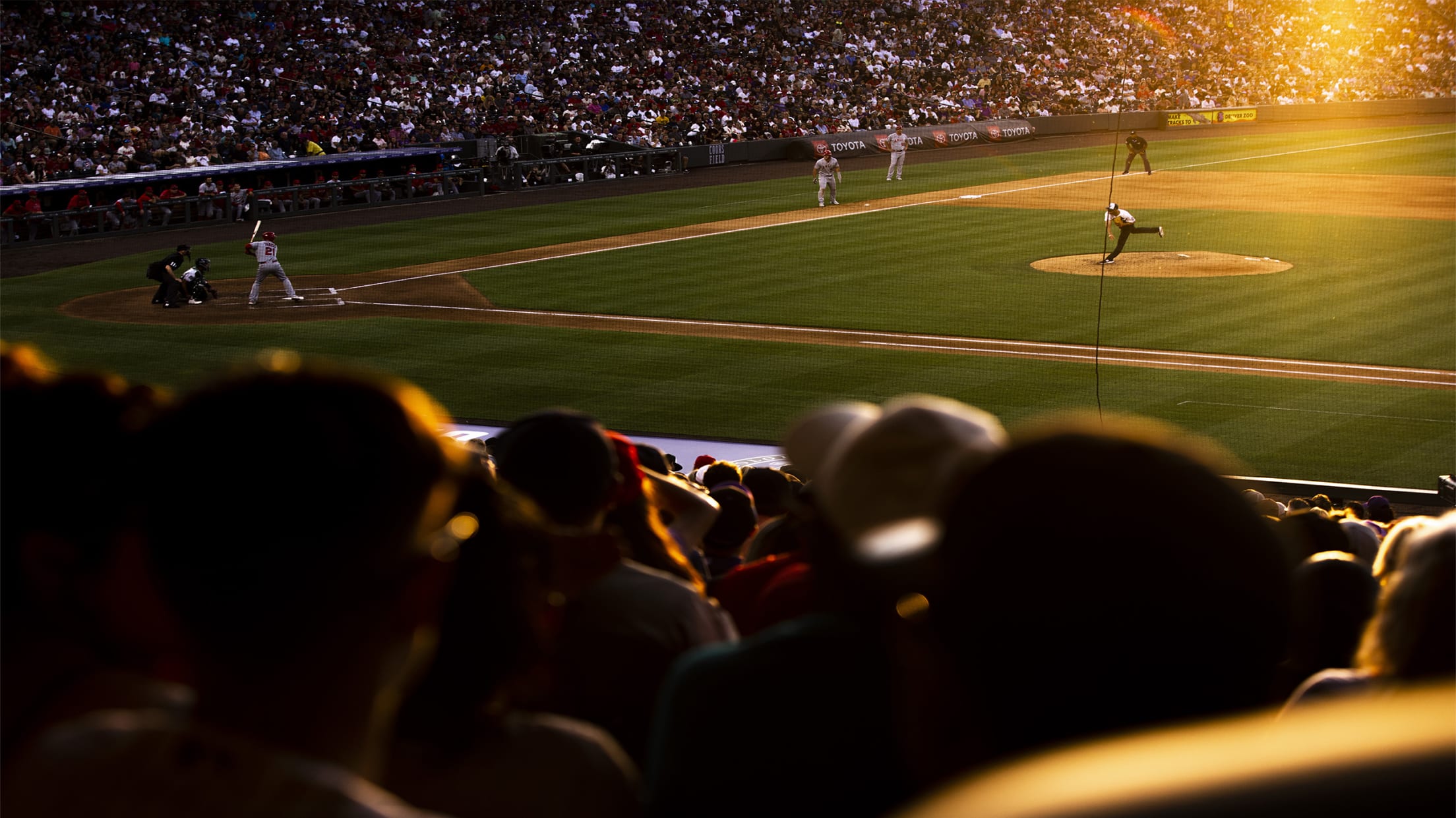 A baseball game in progress at Coors Field: players on a field, spectators in the stands, and an intense atmosphere.
