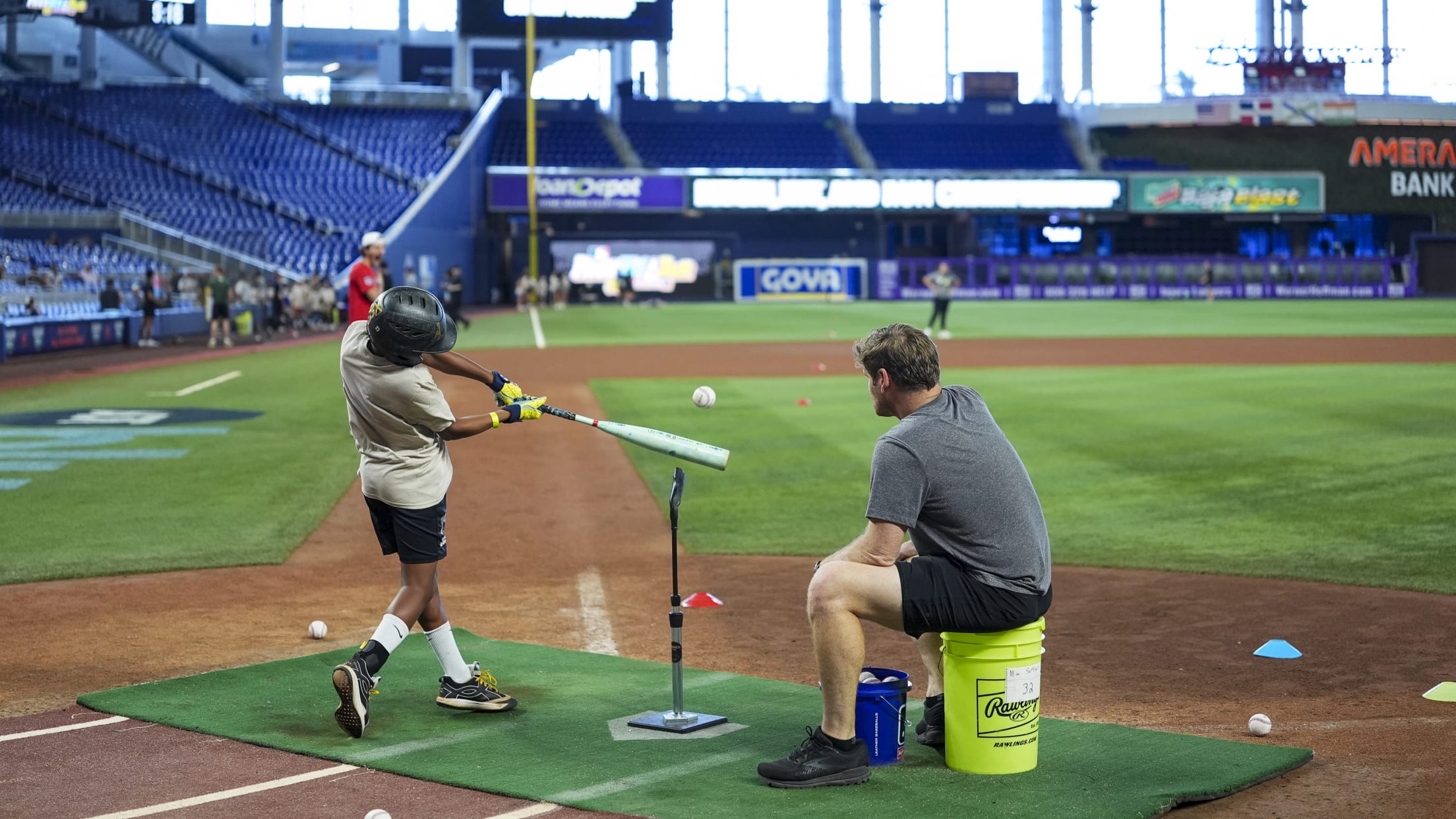 A coach watches as a young player takes a swing off the tee.