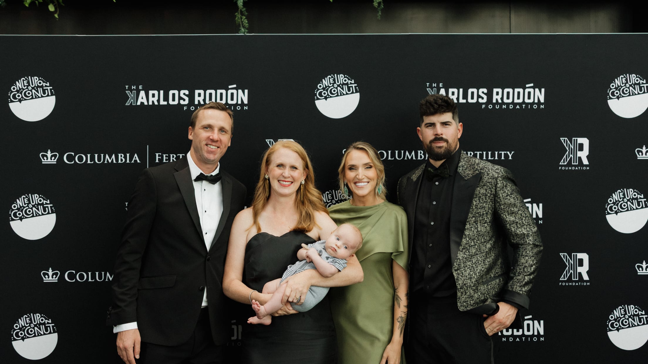 Carlos Rodón and others pose for a photo in front of Columbia University Fertility Center and The Carlos Rodón Foundation signage.