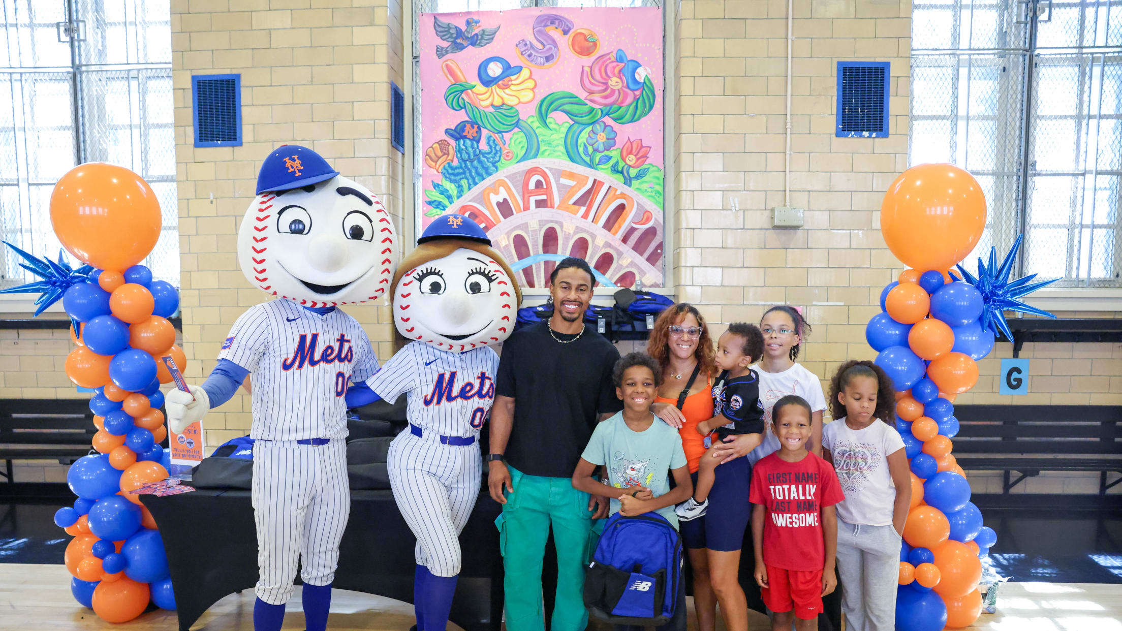 Francisco Lindor takes a photograph with a family receiving a backpack at a New York City school.