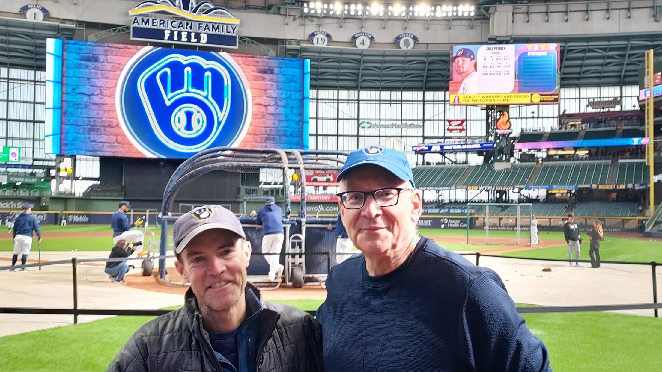Two fans standing on the field during batting practice.