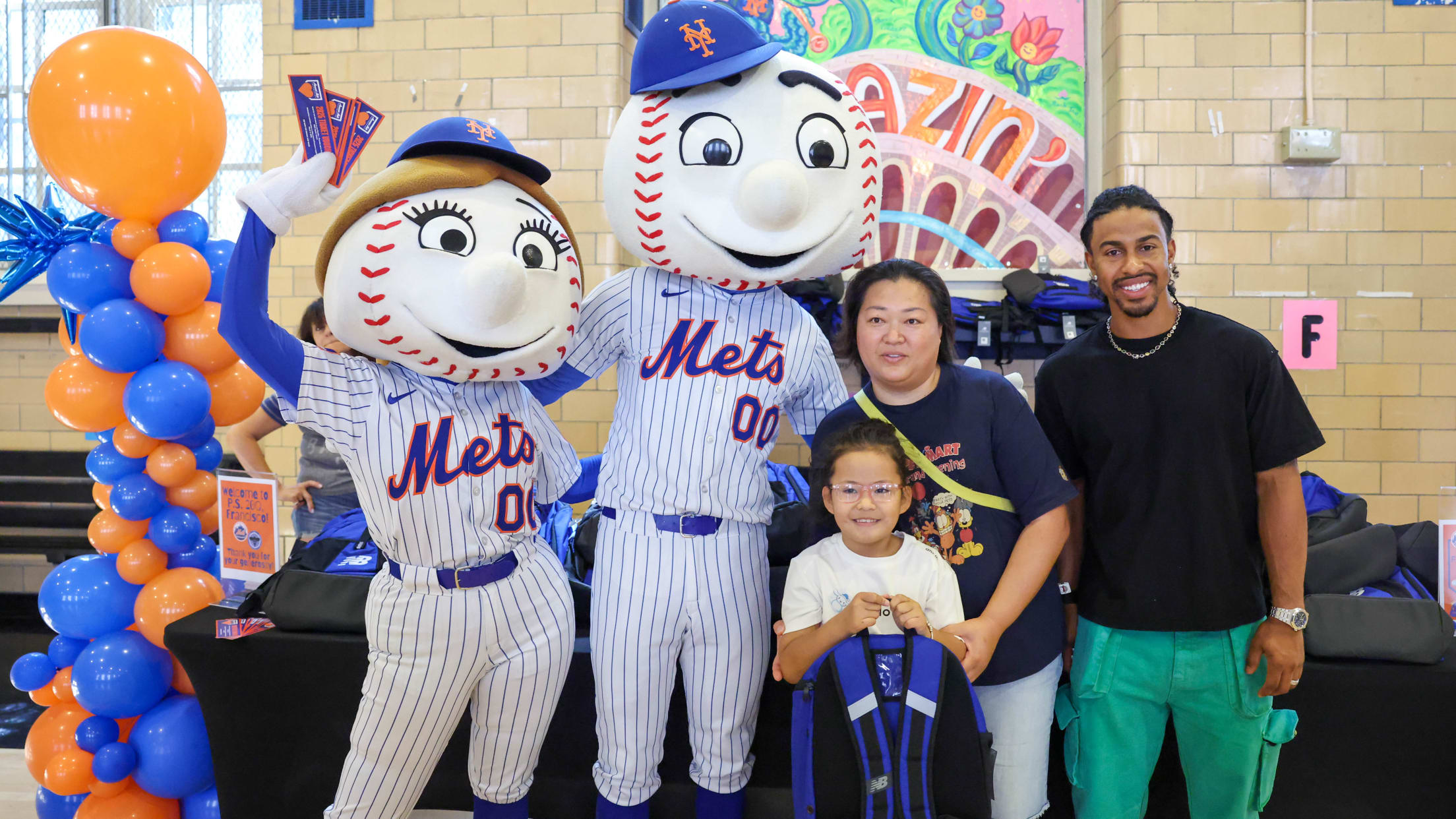 Francisco Lindor alongside Mr. and Mrs. Met take a picture with fans receiving a backpack at a New York City school.