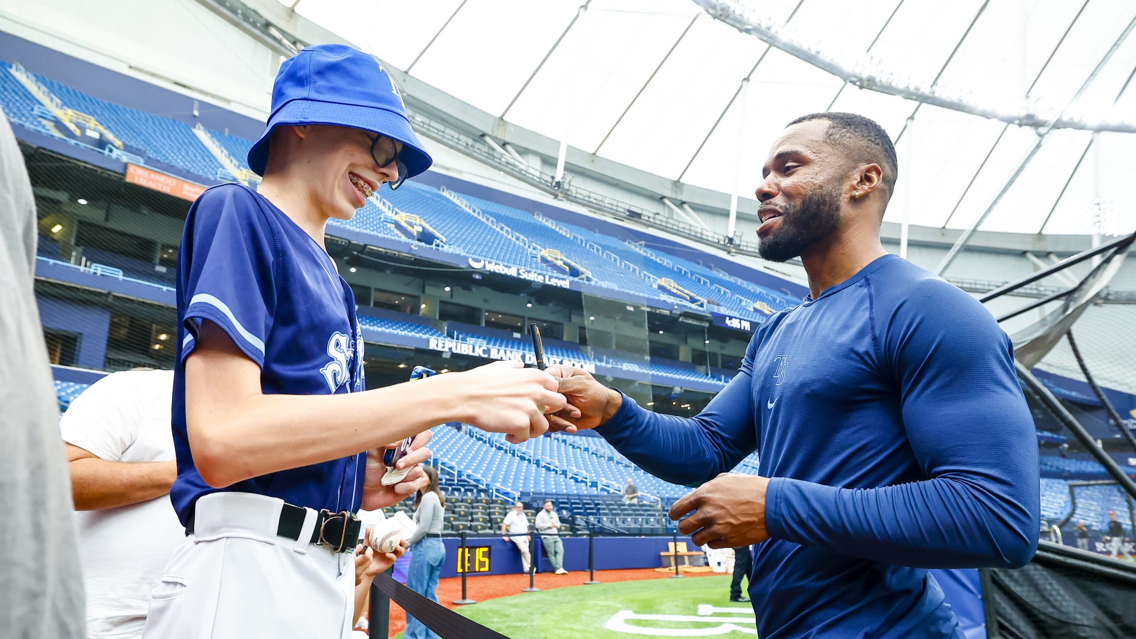 Cedric Mullins signs a baseball for a happy Tampa Bay Rays fan.