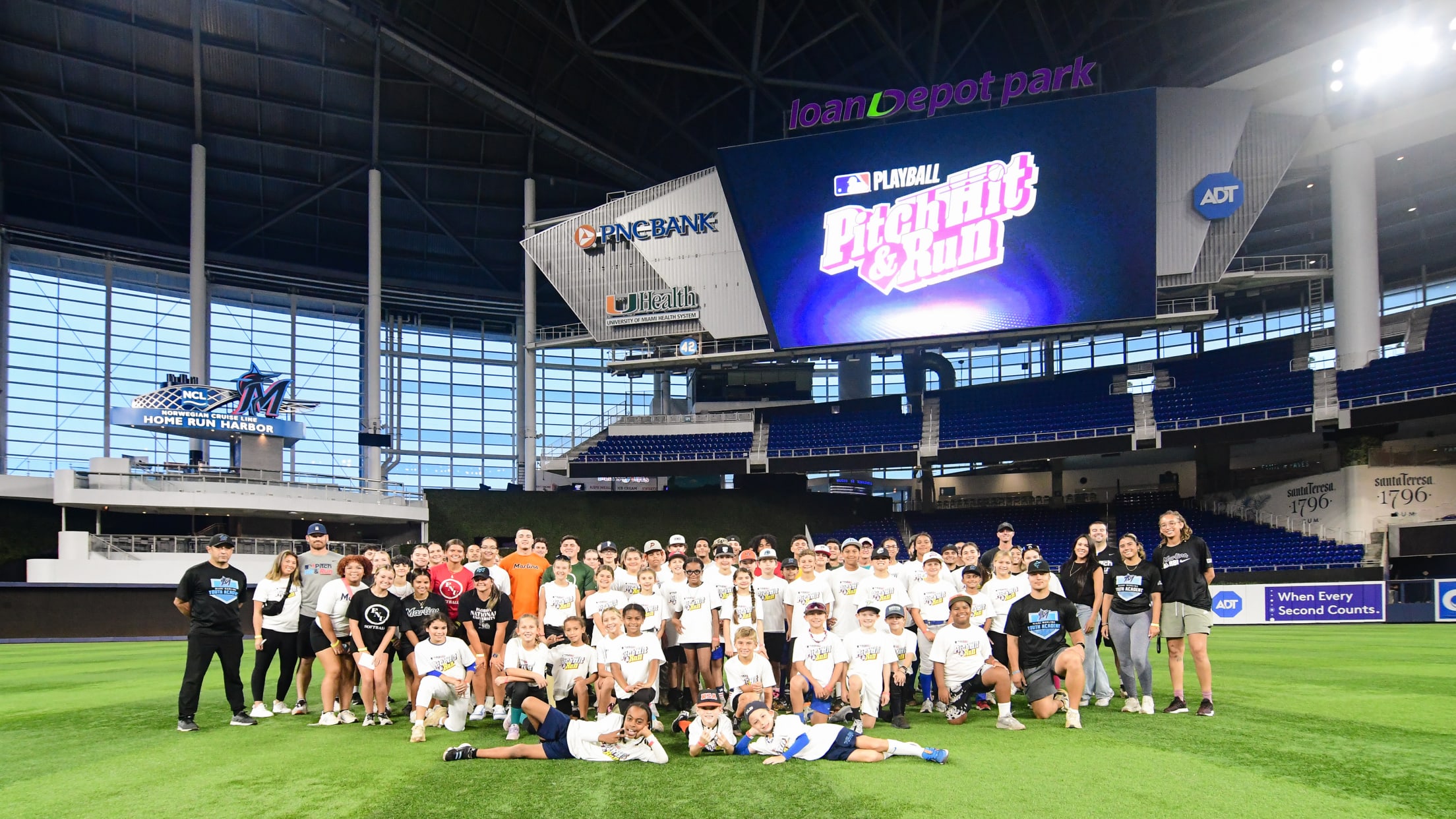 Players and coaches of Pitch, Hit & Run take a photo on the field at loanDepot Park.