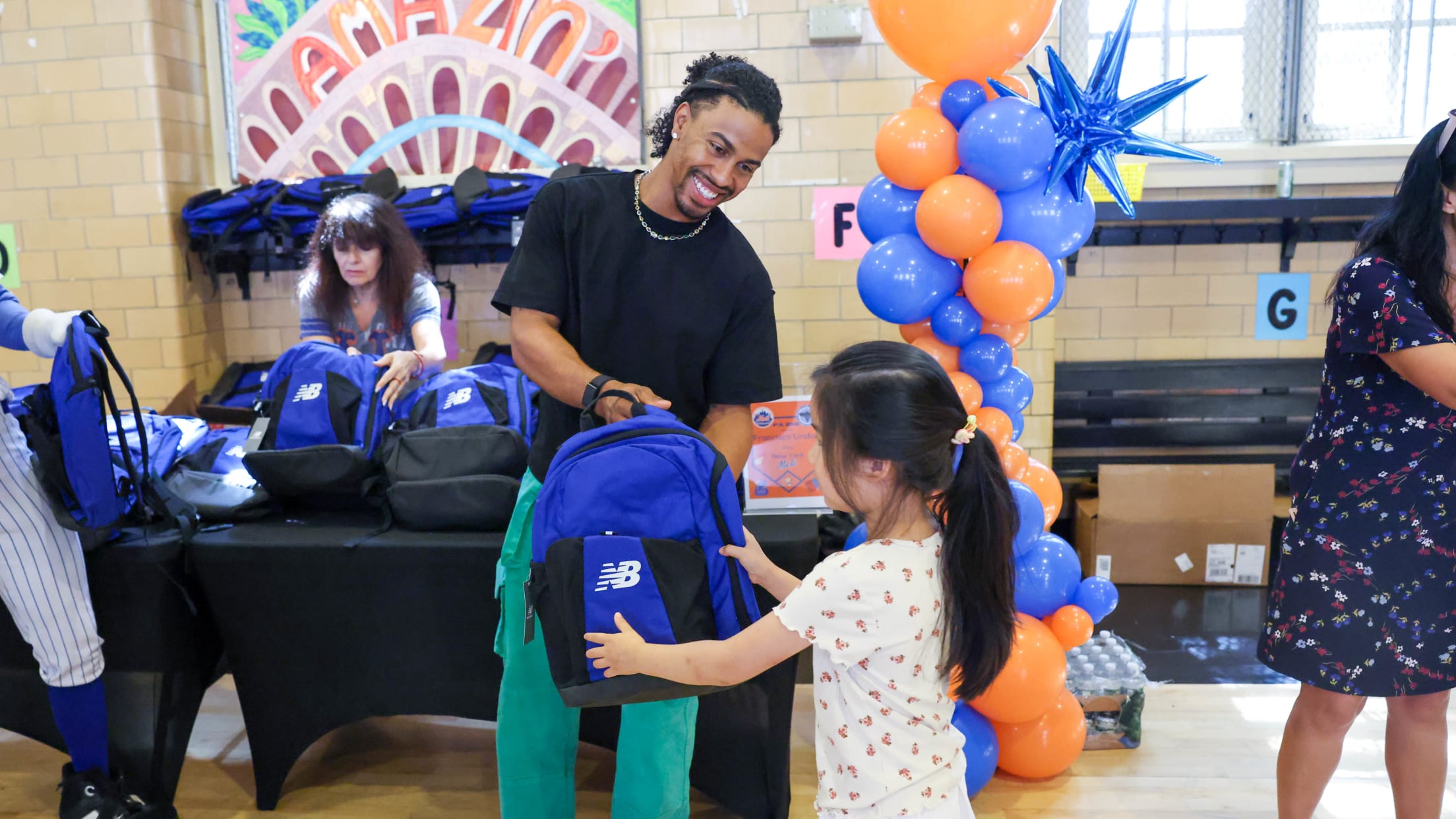 Francisco Lindor hands a student a New Balance backpack at a school supply giveaway.