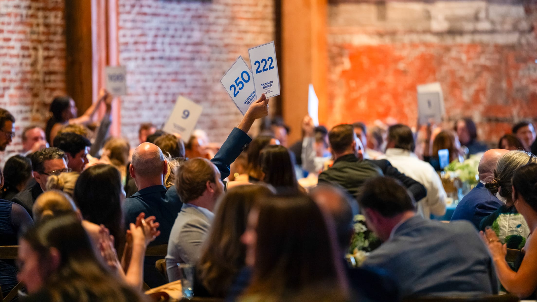 Image of people bidding at live auction.