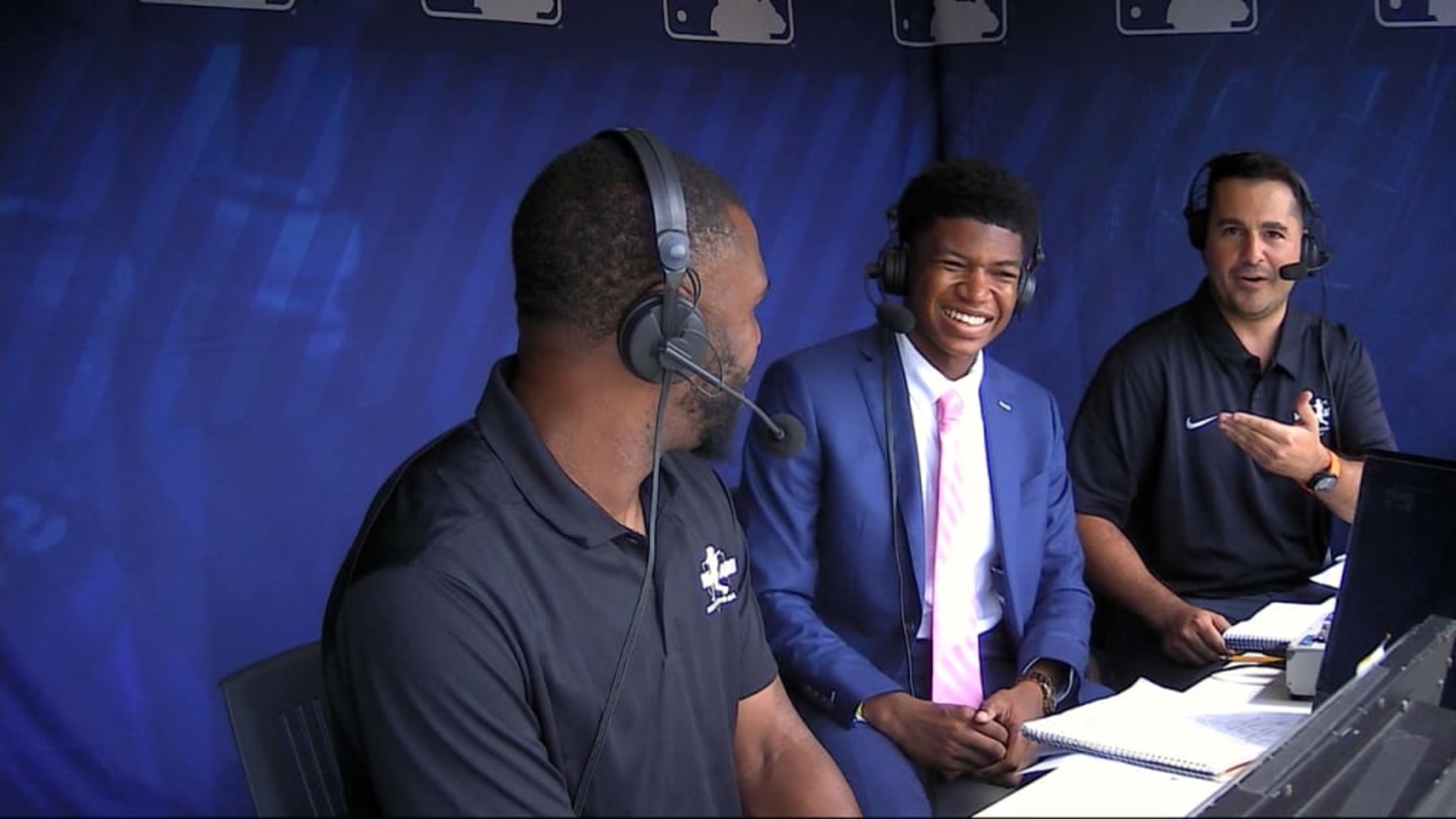 Three men in the broadcasting booth at a baseball game.