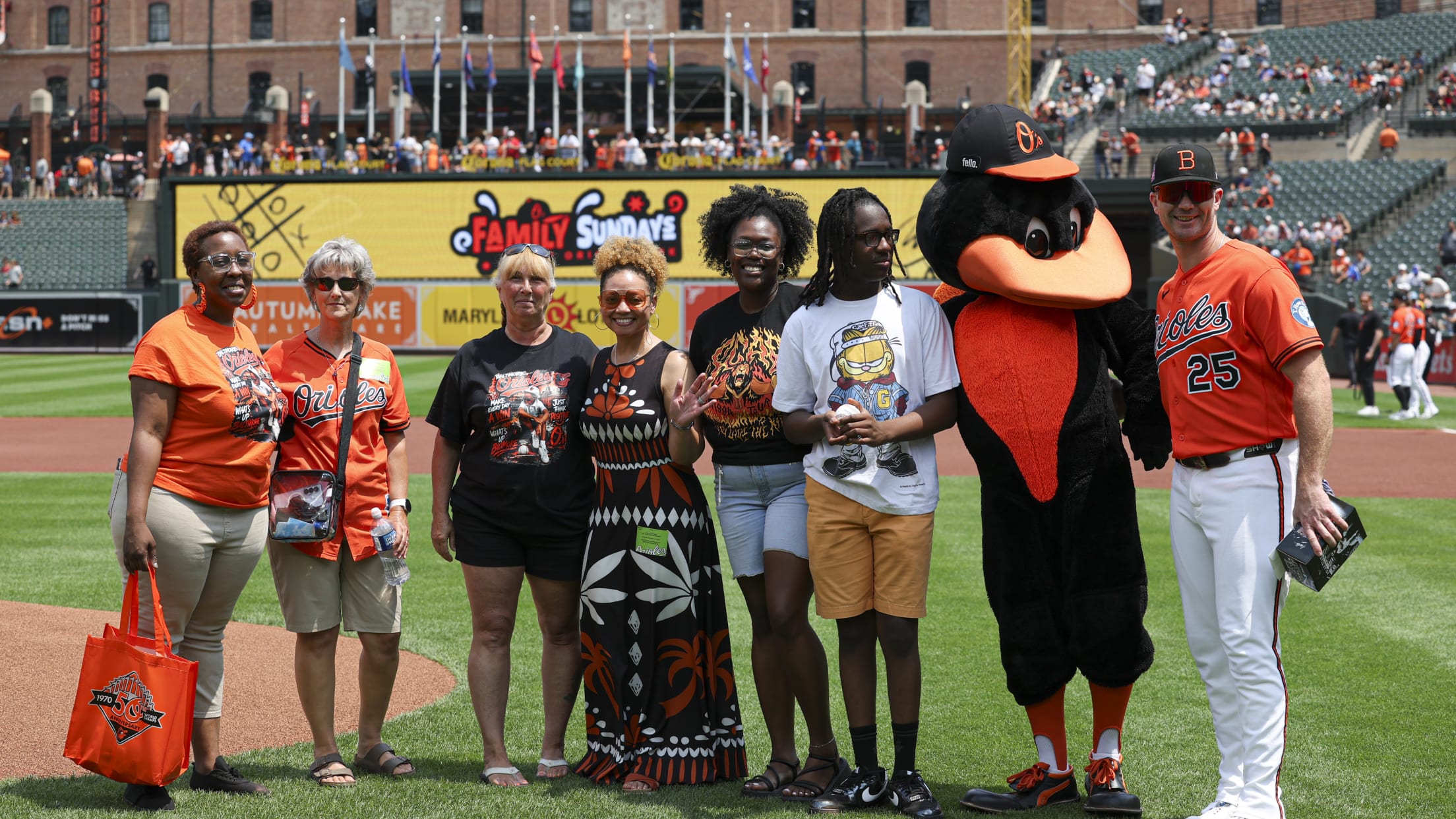 Pete Alonso takes a picture with fans and The Oriole Bird on the field at Camden Yards.