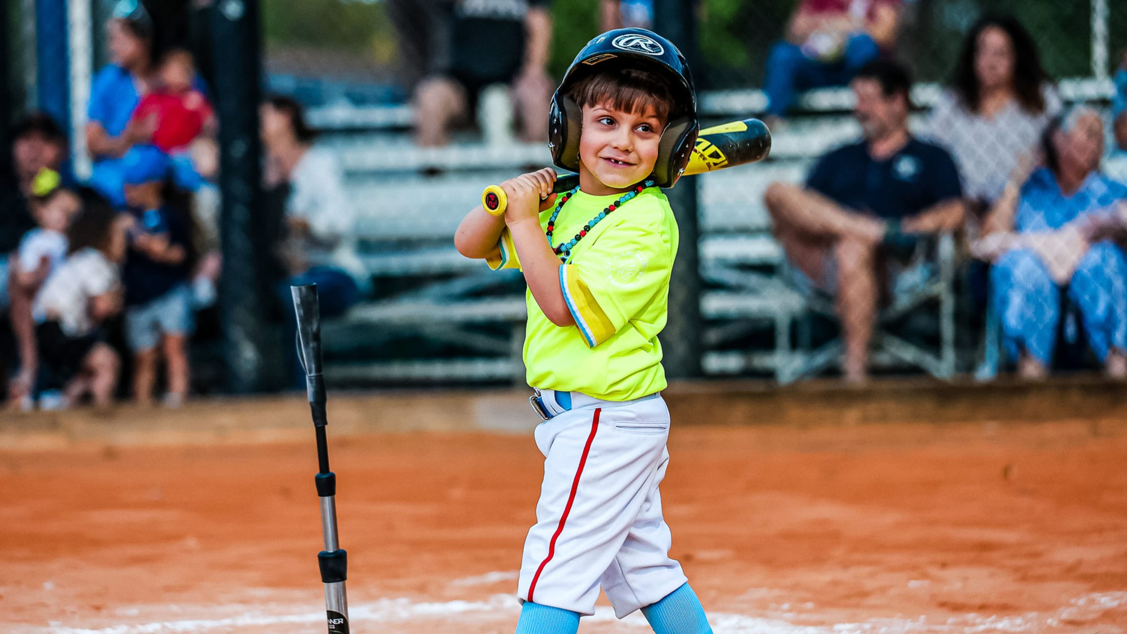 A Miami Marlins Youth Academy athlete stands with a bat next to a tee by home plate.