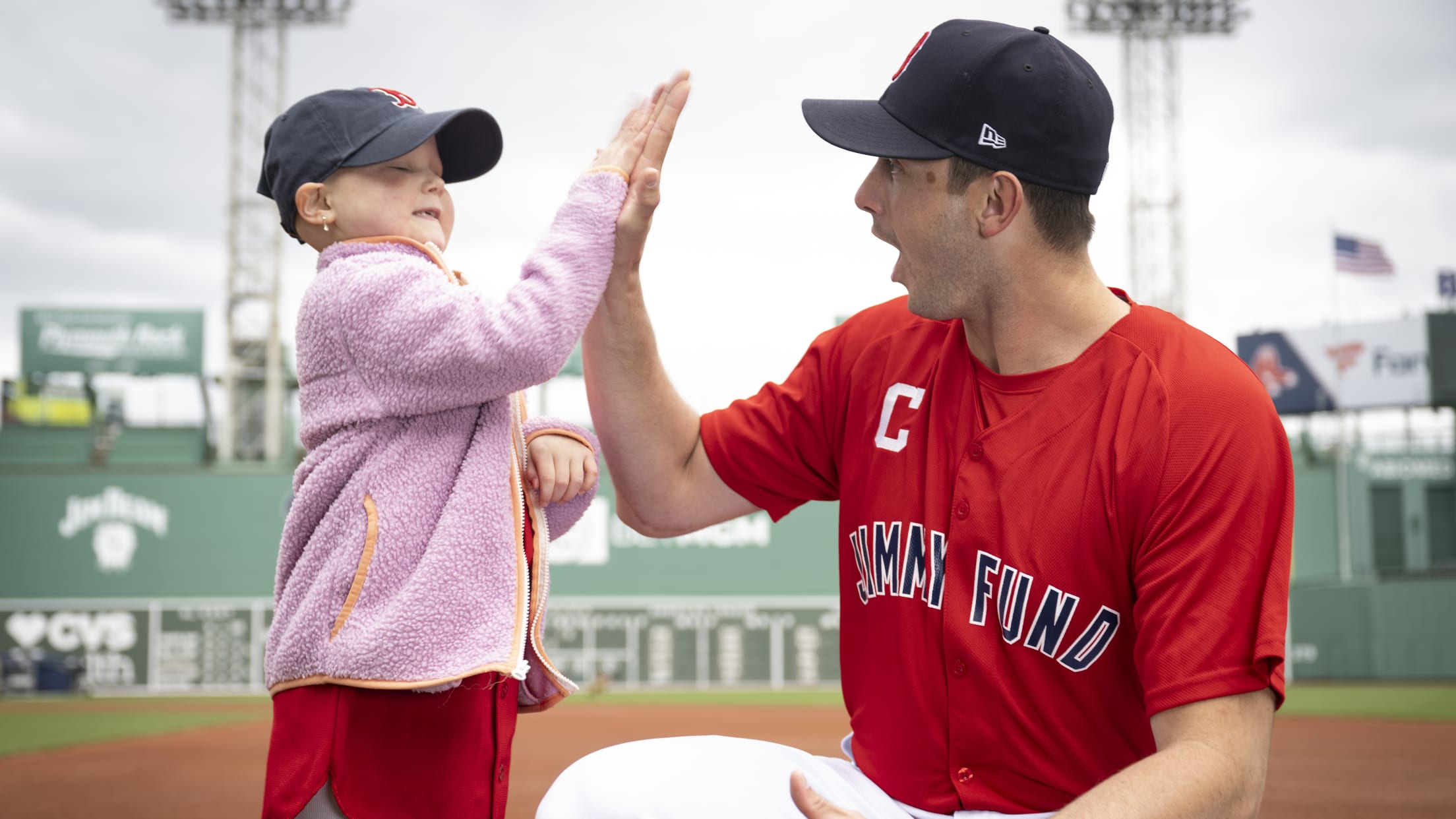 Garrett Whitlock, a Jimmy Fund Captain, high-fives a Boston Red Sox fan.