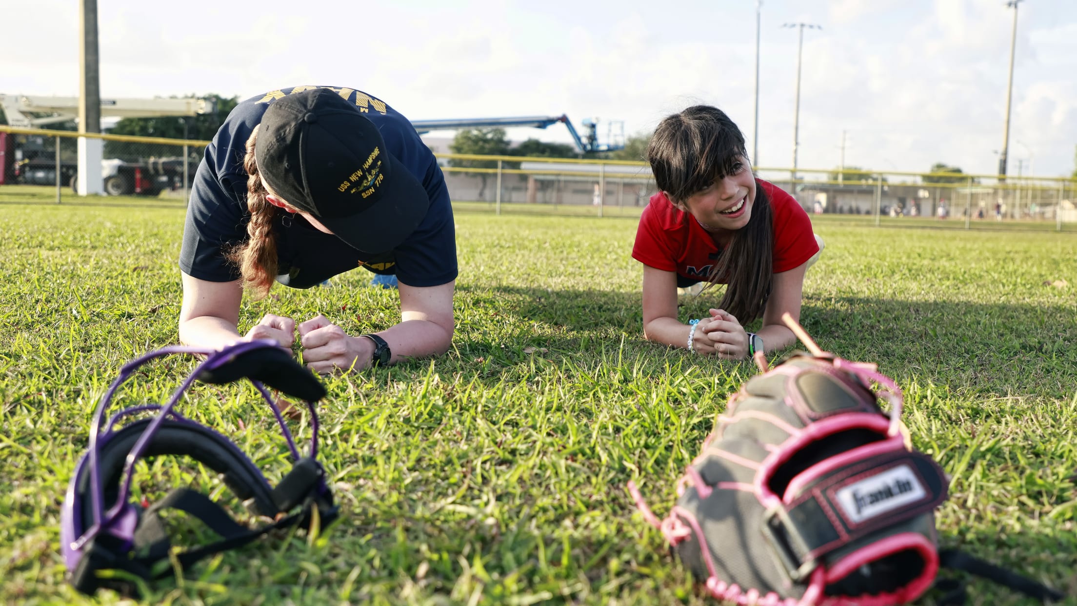 A player and Navy service member practice their planking on the field.