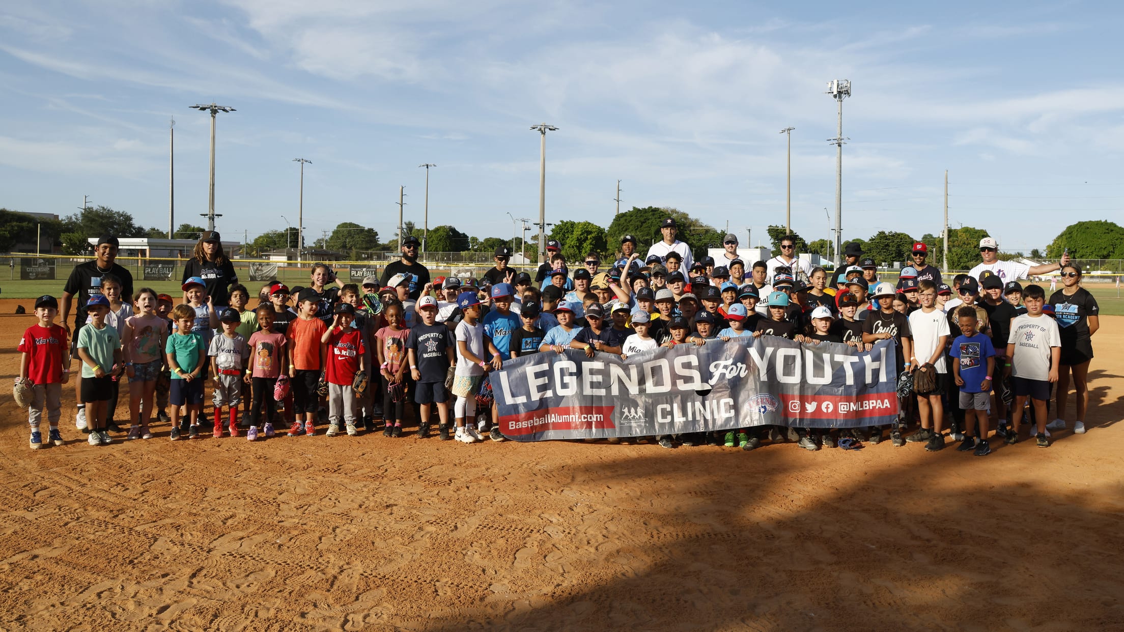 Players take a group photo with the MLBPAA Legends for Youth Clinic banner.