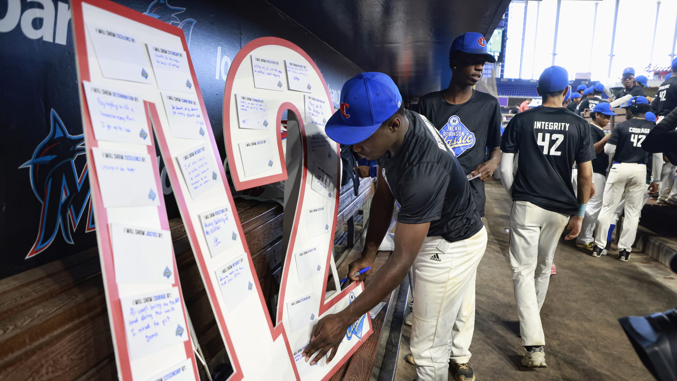 Players hang out in the dugout in front of Jackie Robinson's number 42.
