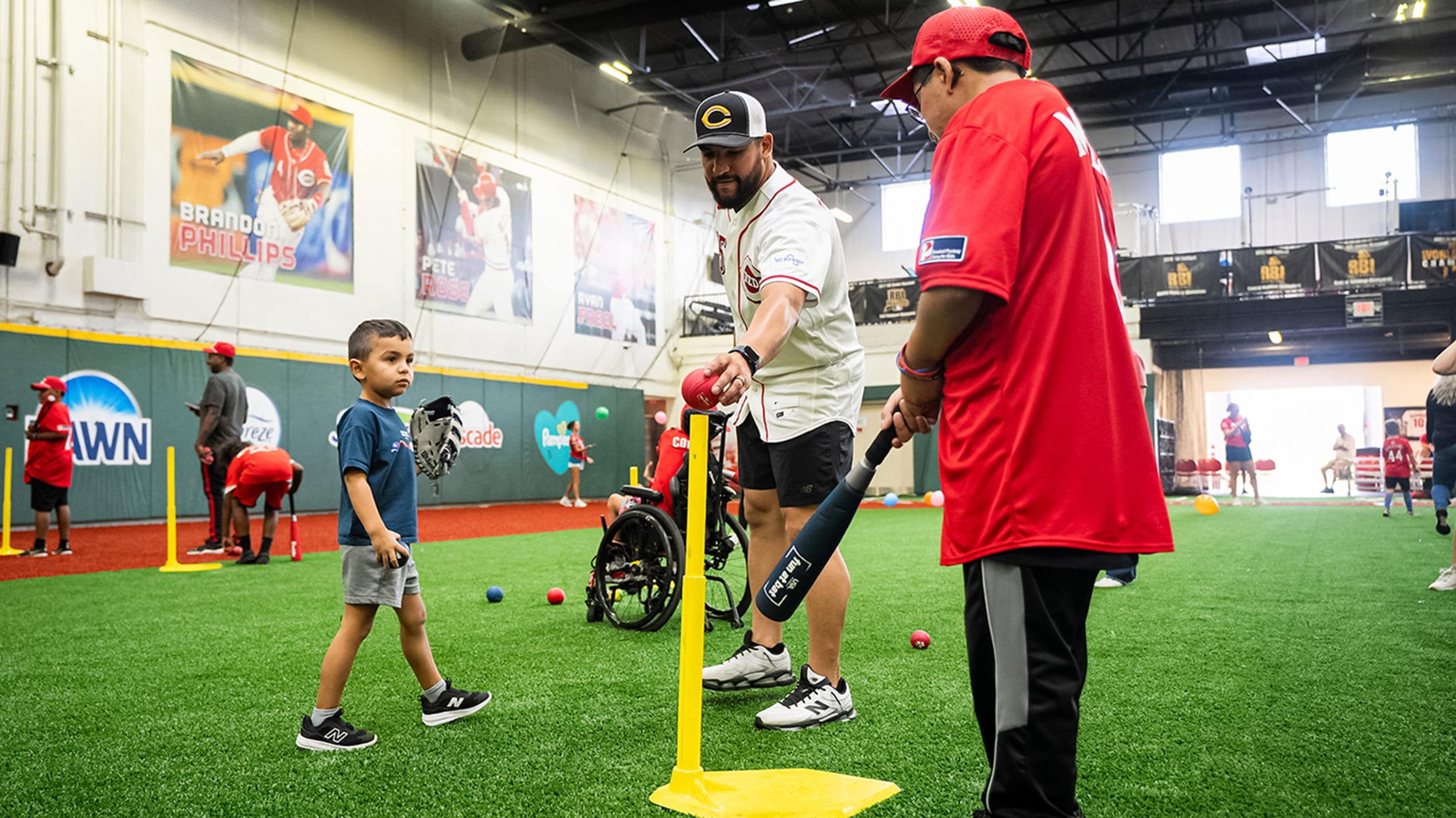 Jose Trevino sets a ball on the tee for a young participant at the camp.