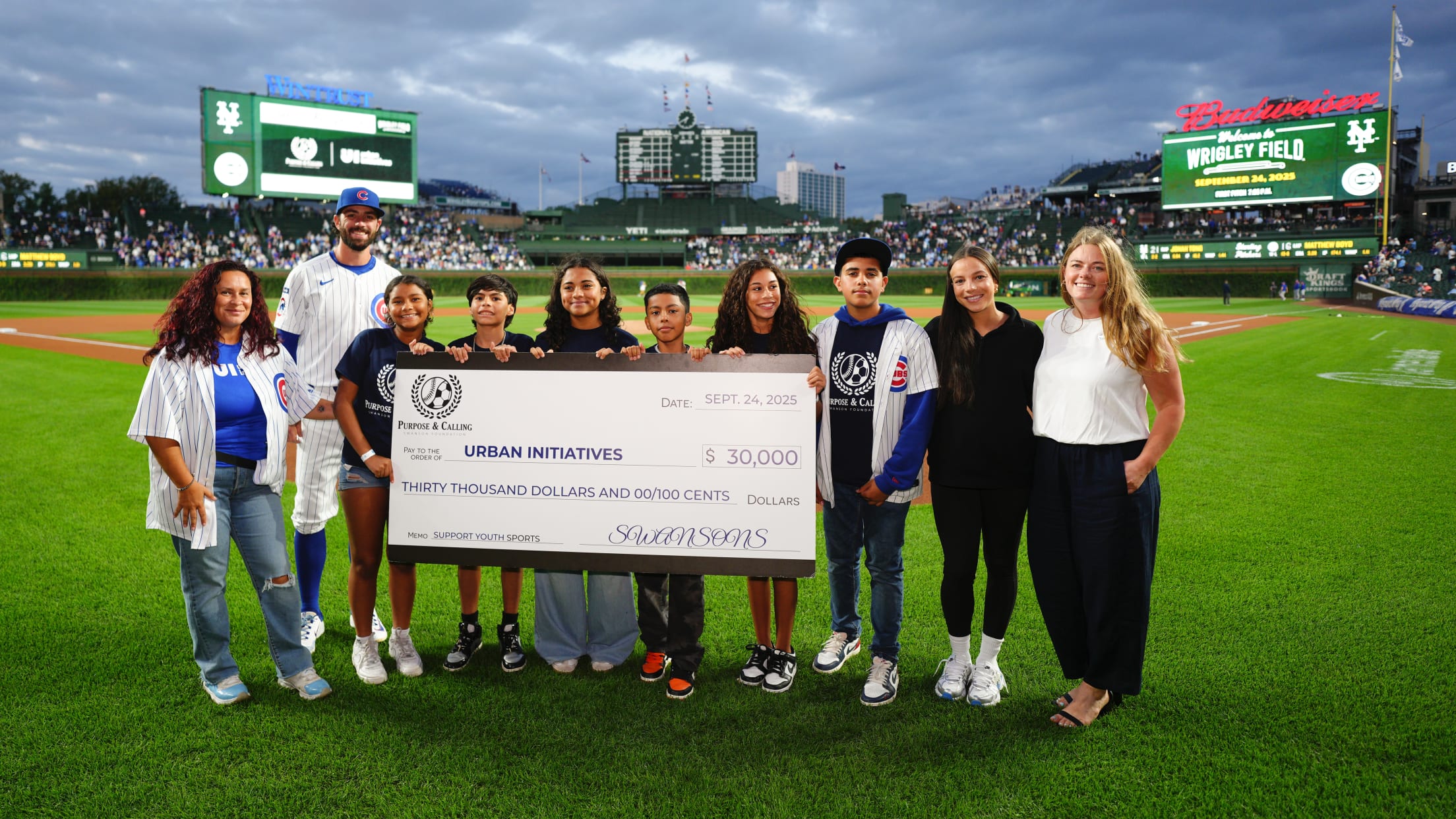 Dansby Swanson presents a check to Urban Initiatives during pregame ceremonies at Wrigley Field.
