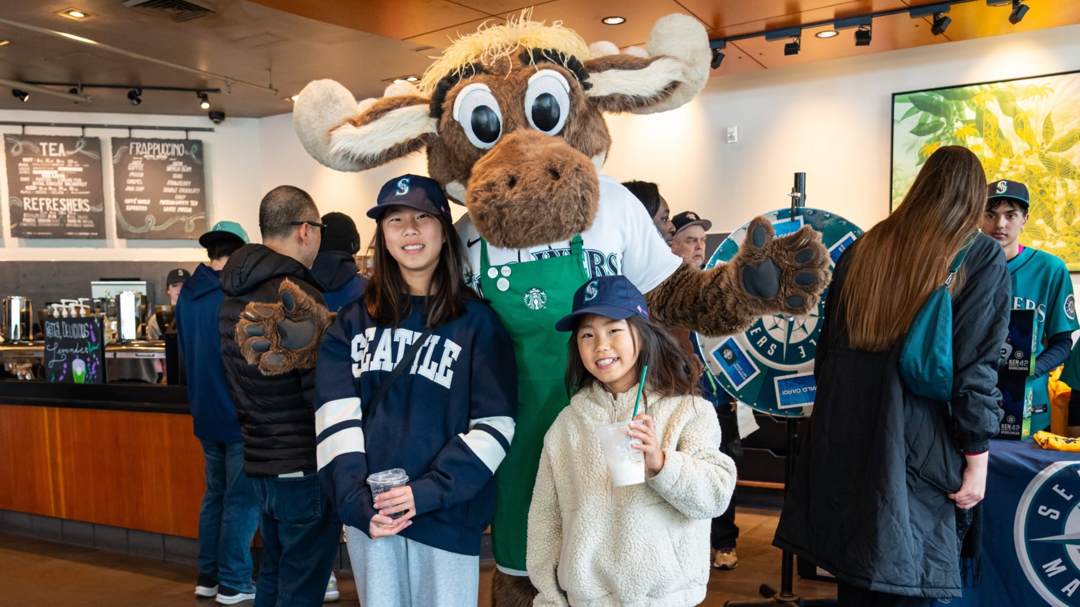 Mariner Moose posing with fans at Starbucks cafe.
