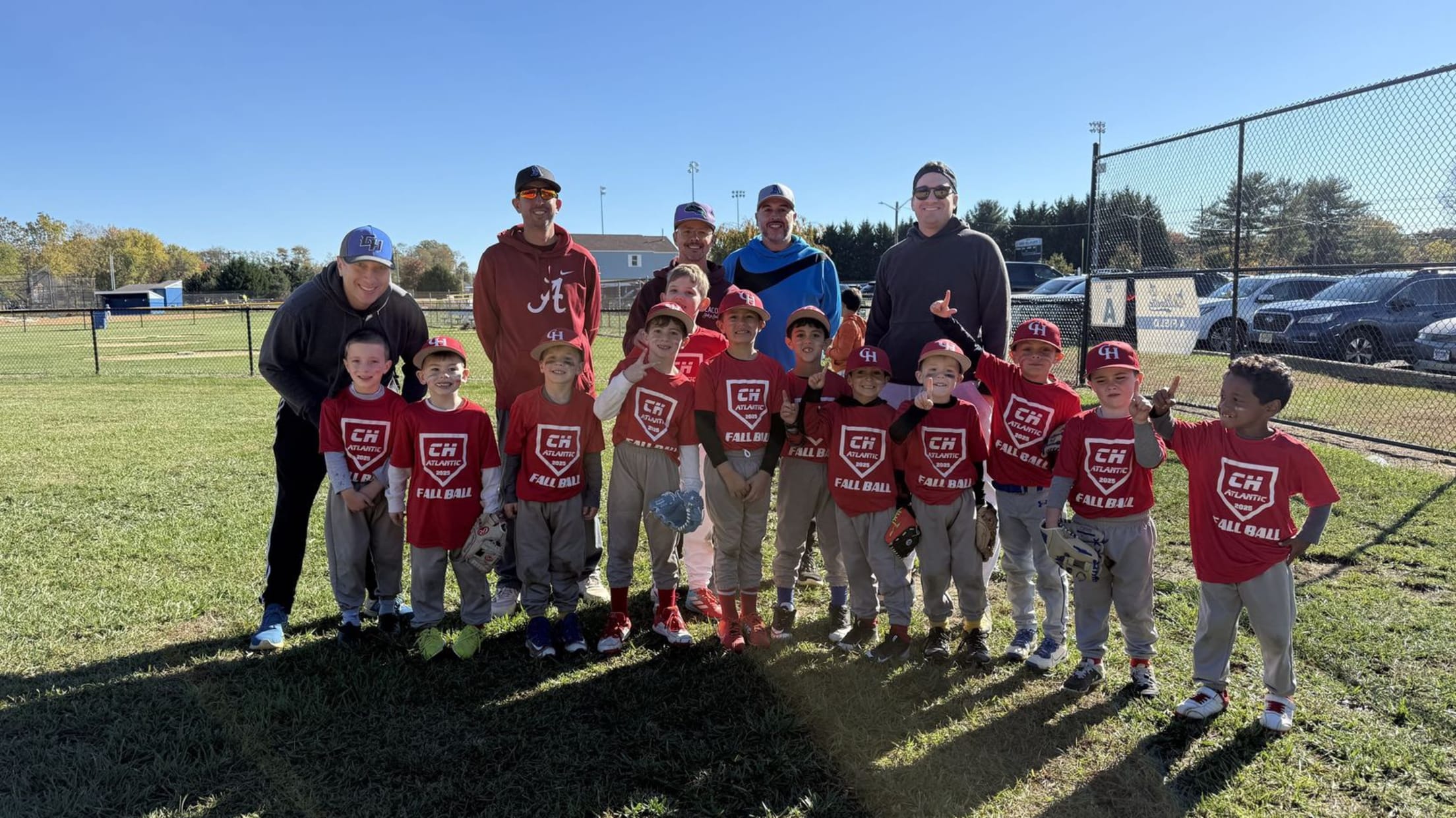 A youth baseball team stands in a field with coaches.