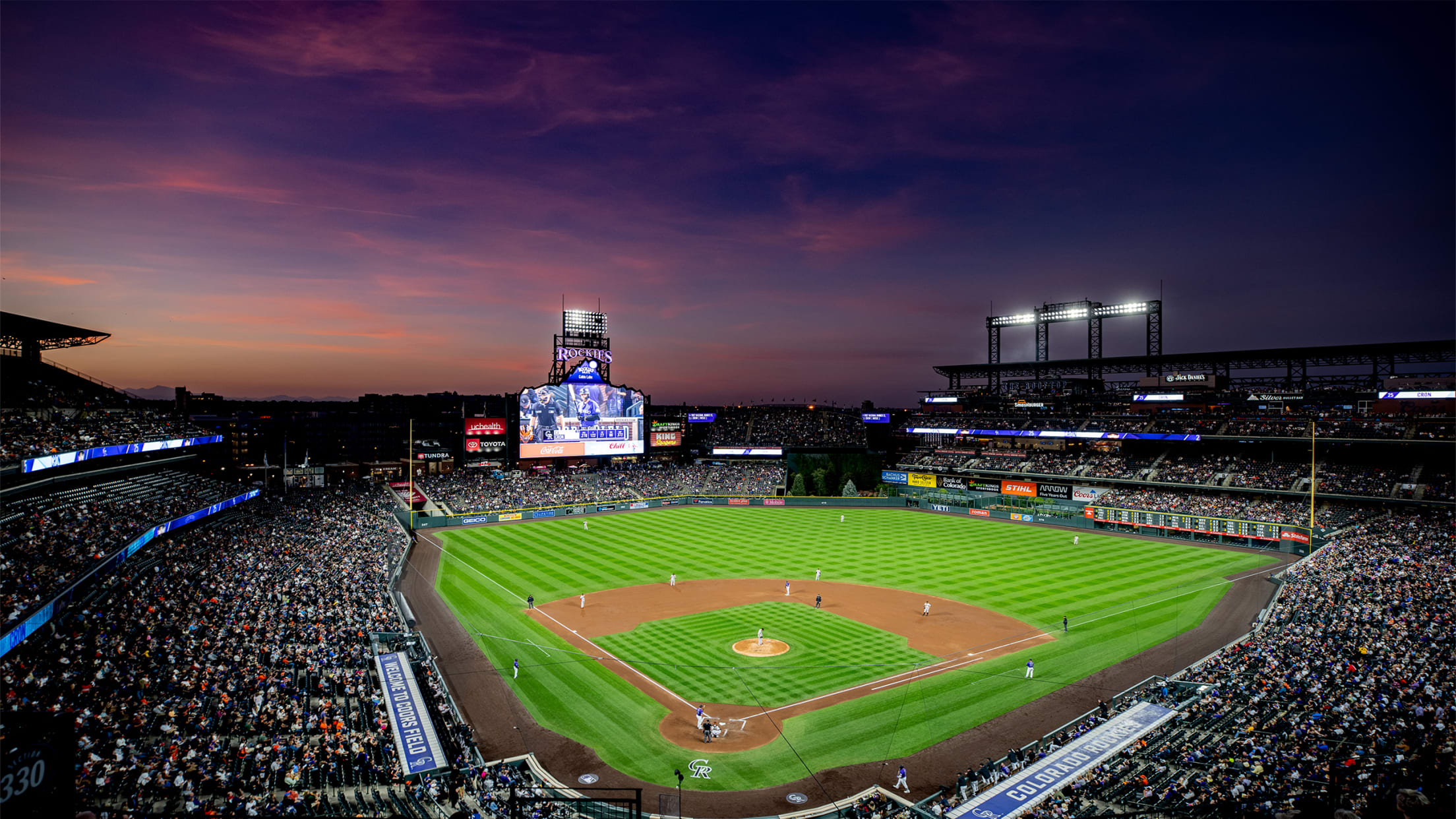 Inside Coors Field from behind Homeplate from the 3rd level with a sunset as your backdrop