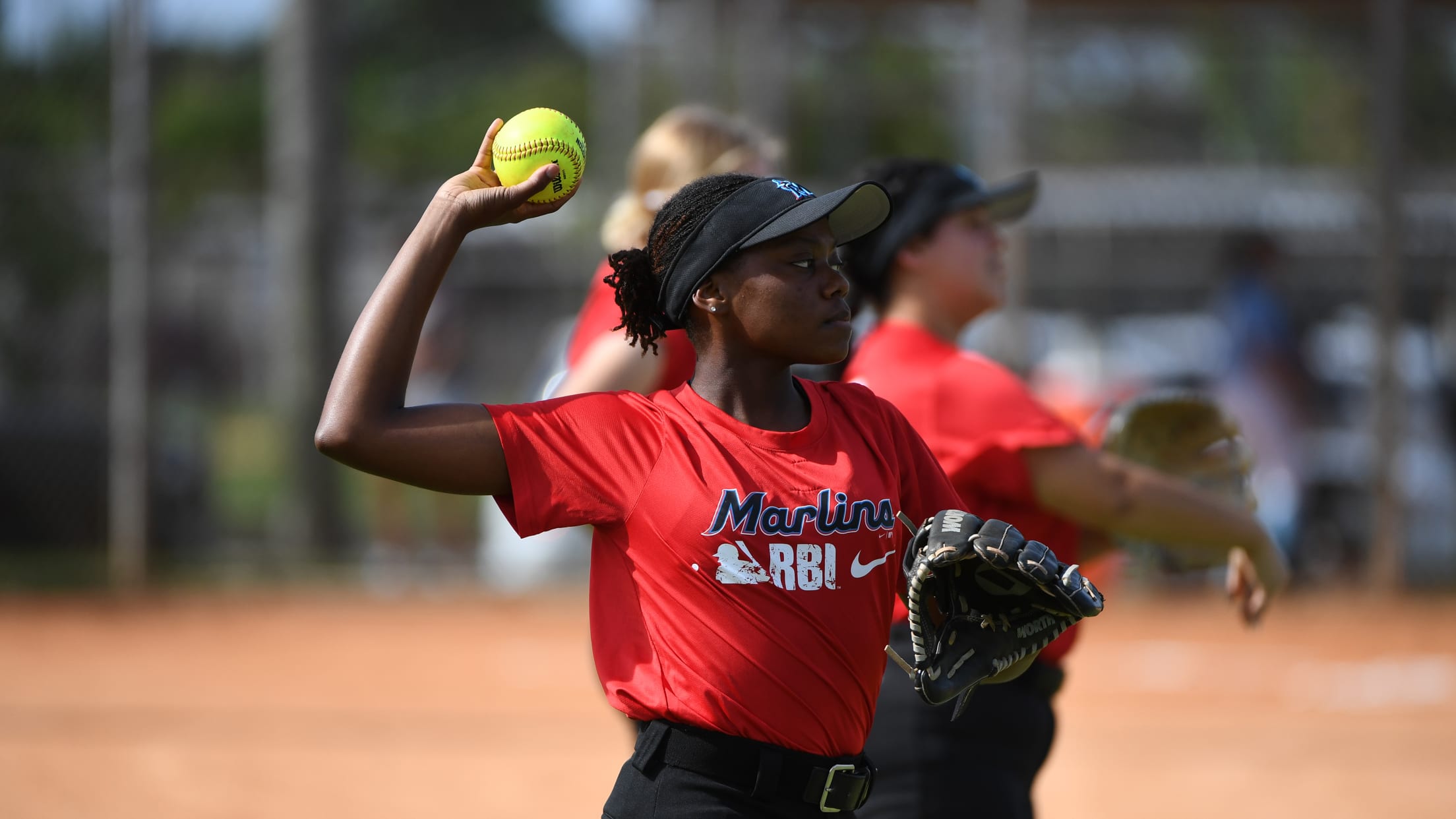A softball player winds up to throw the ball at Marlins Nike RBI Opening Day.