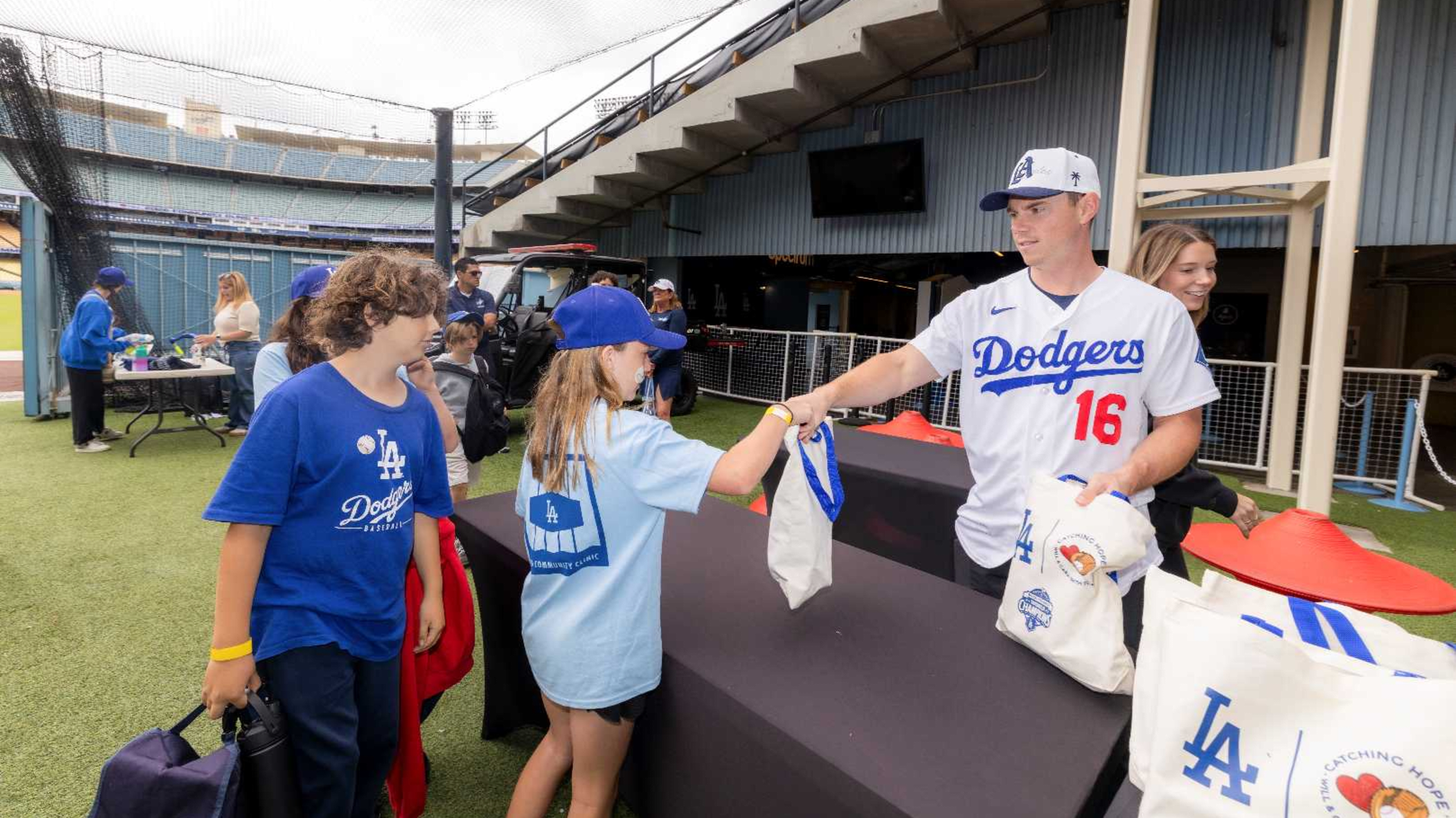 Will Smith hands out Dodges bags to kids at an event at Dodger Stadium.