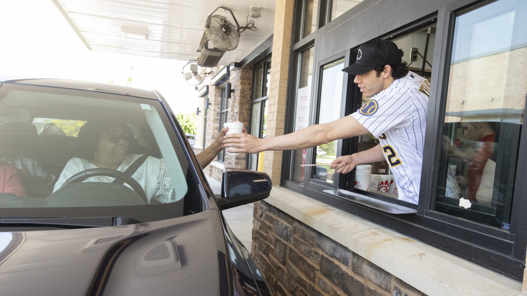 Christian Yelich hands a customer a drink at a drive thru at Chick-fil-A.