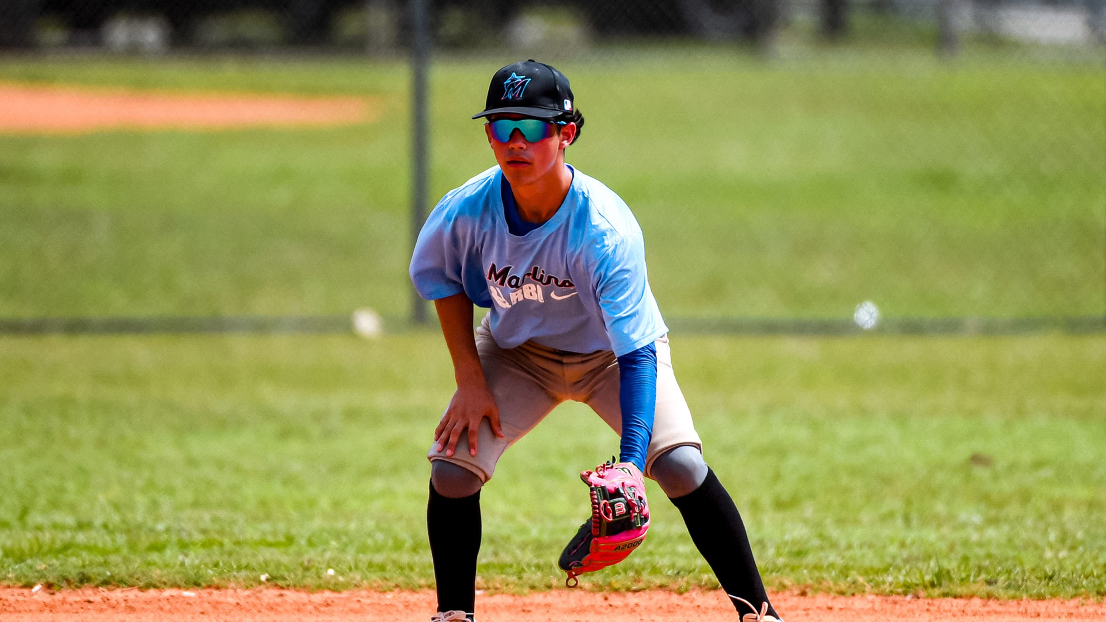 A Marlins RBI athlete stands on the infield ready to field a ground ball.