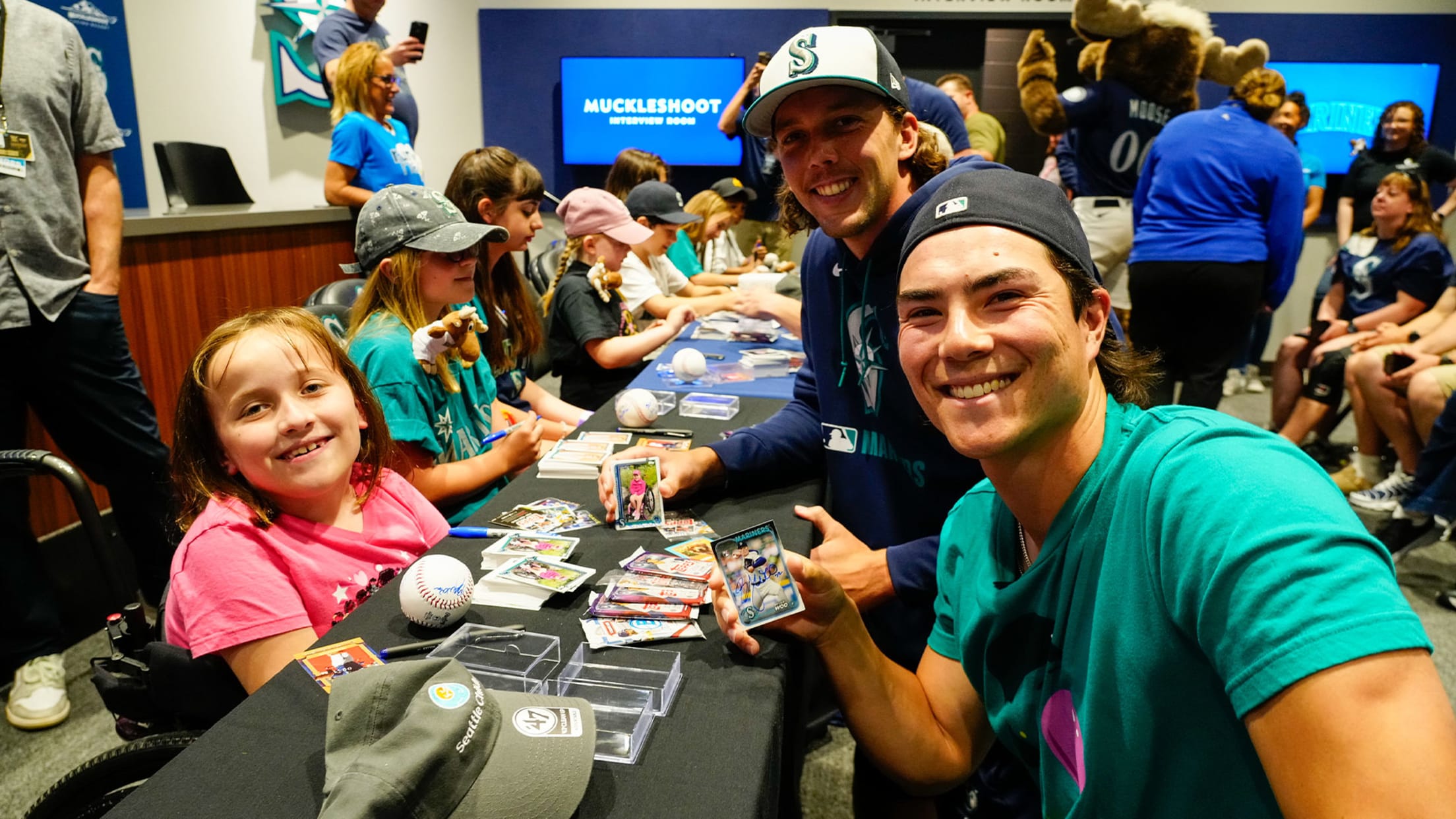 Image of Bryan Woo and Logan Gilbert signing for fans at charity event.