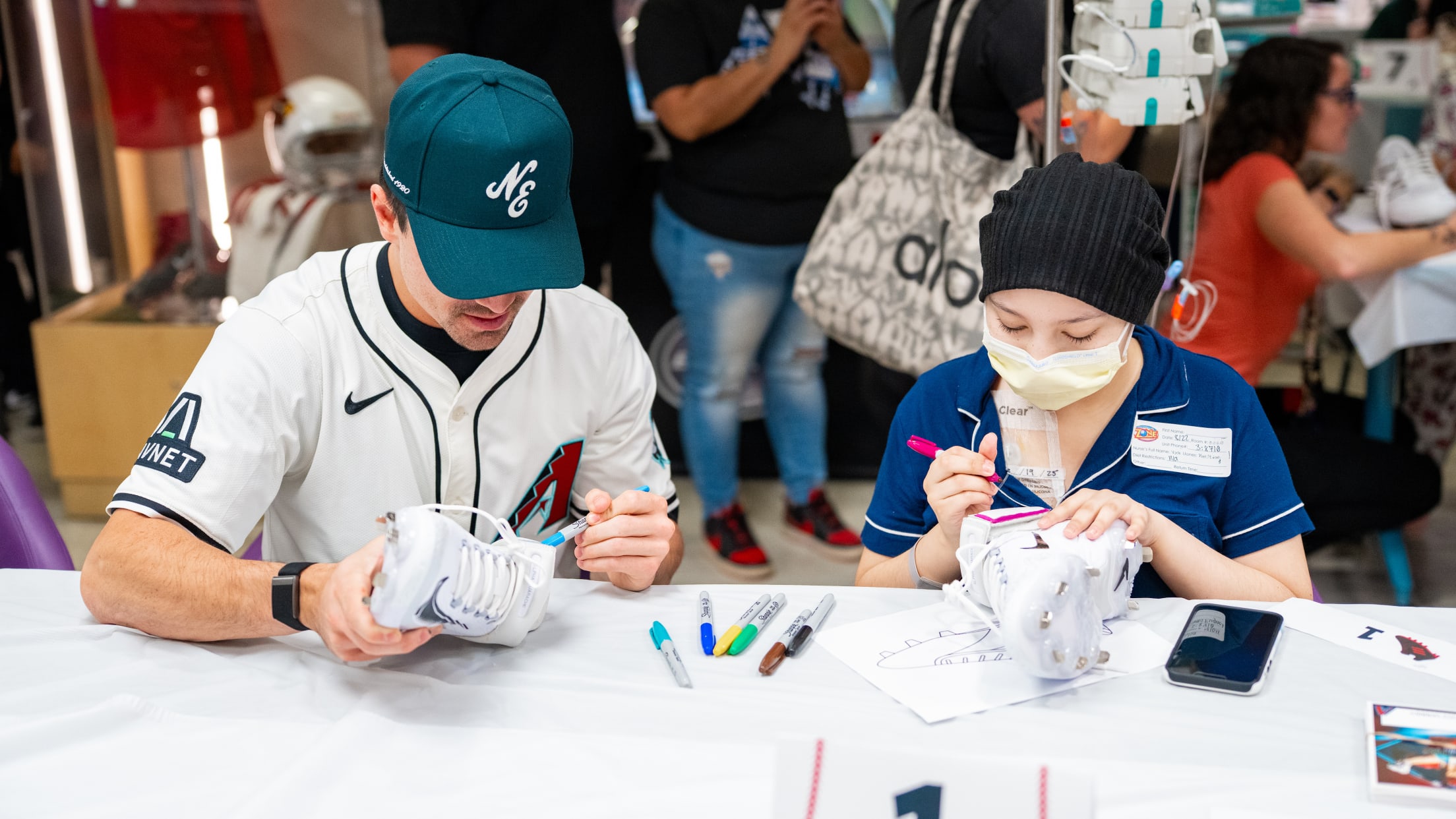 Corbin Carroll decorates cleats with a fan participating in Cleats for a Cause at Phoenix Children's Hospital.