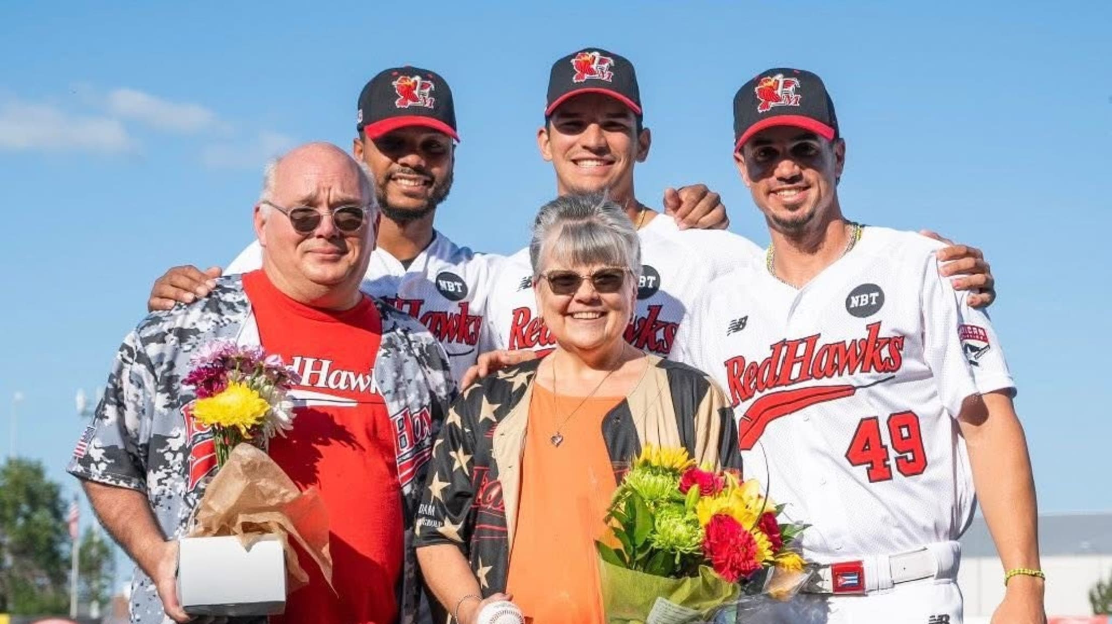 Three players and two fans take a picture before a Red Hawks game.