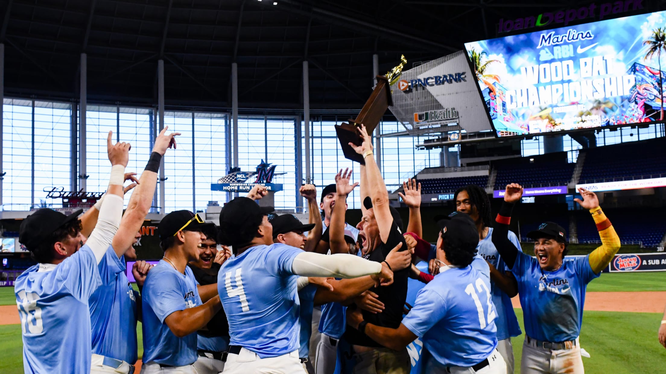 Players celebrate and hoist the trophy at the Wood Bat Classic.
